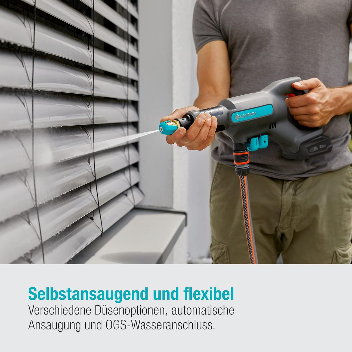 Mann benutzt einen grau-türkisen Hochdruckreiniger auf einem weißen Fensterladen, Wasser spritzt heraus.