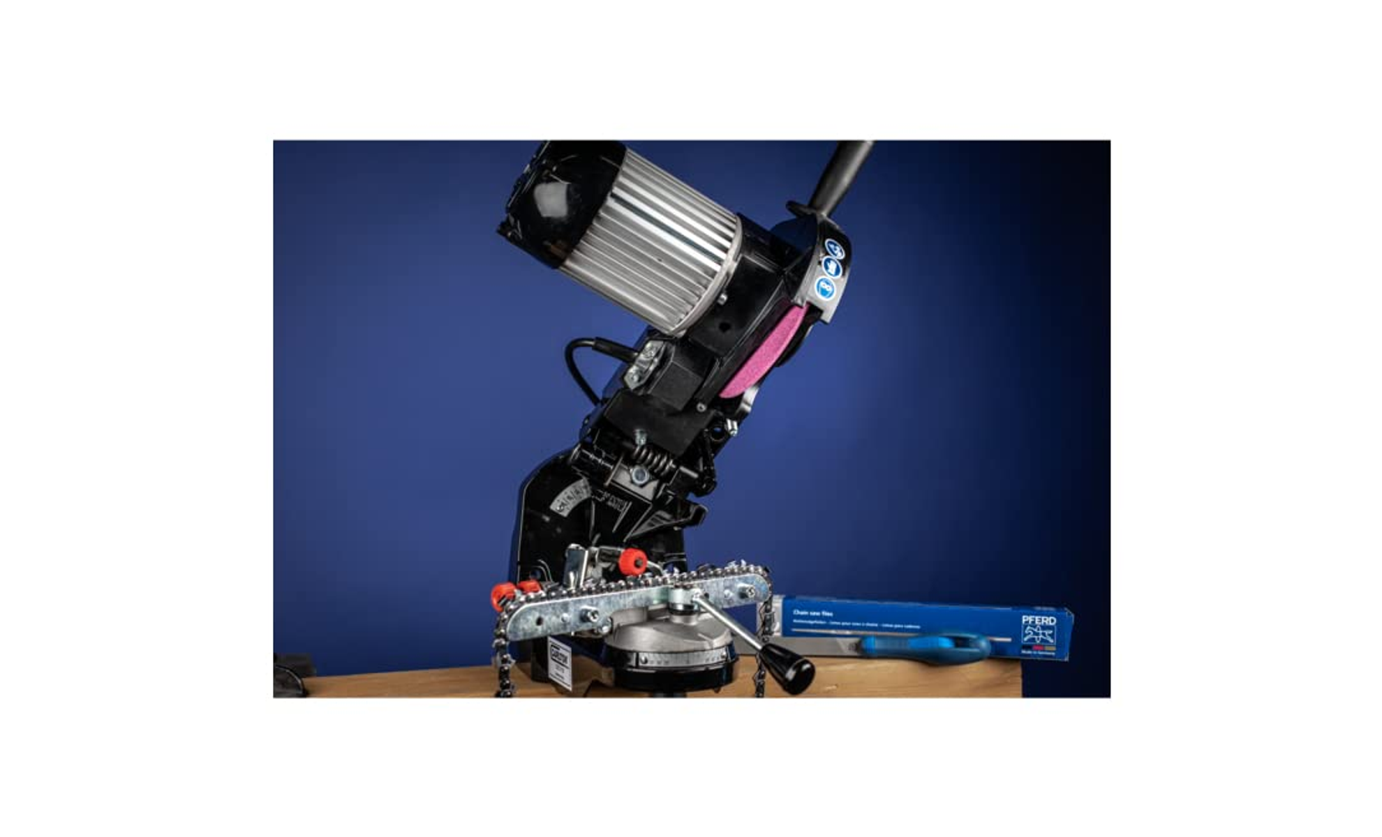 Kettensägen-Schleifmaschine auf Tisch. Blauer Hintergrund, Werkzeugkasten und Teile.