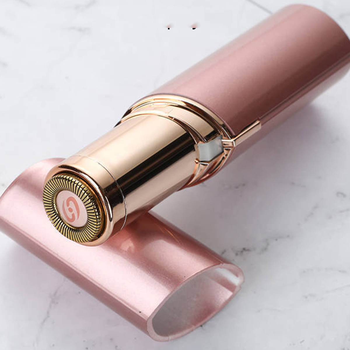 Ein roségoldfarbener elektrischer Rasierer ohne Kopfkappe, platziert auf einer Marmoroberfläche.