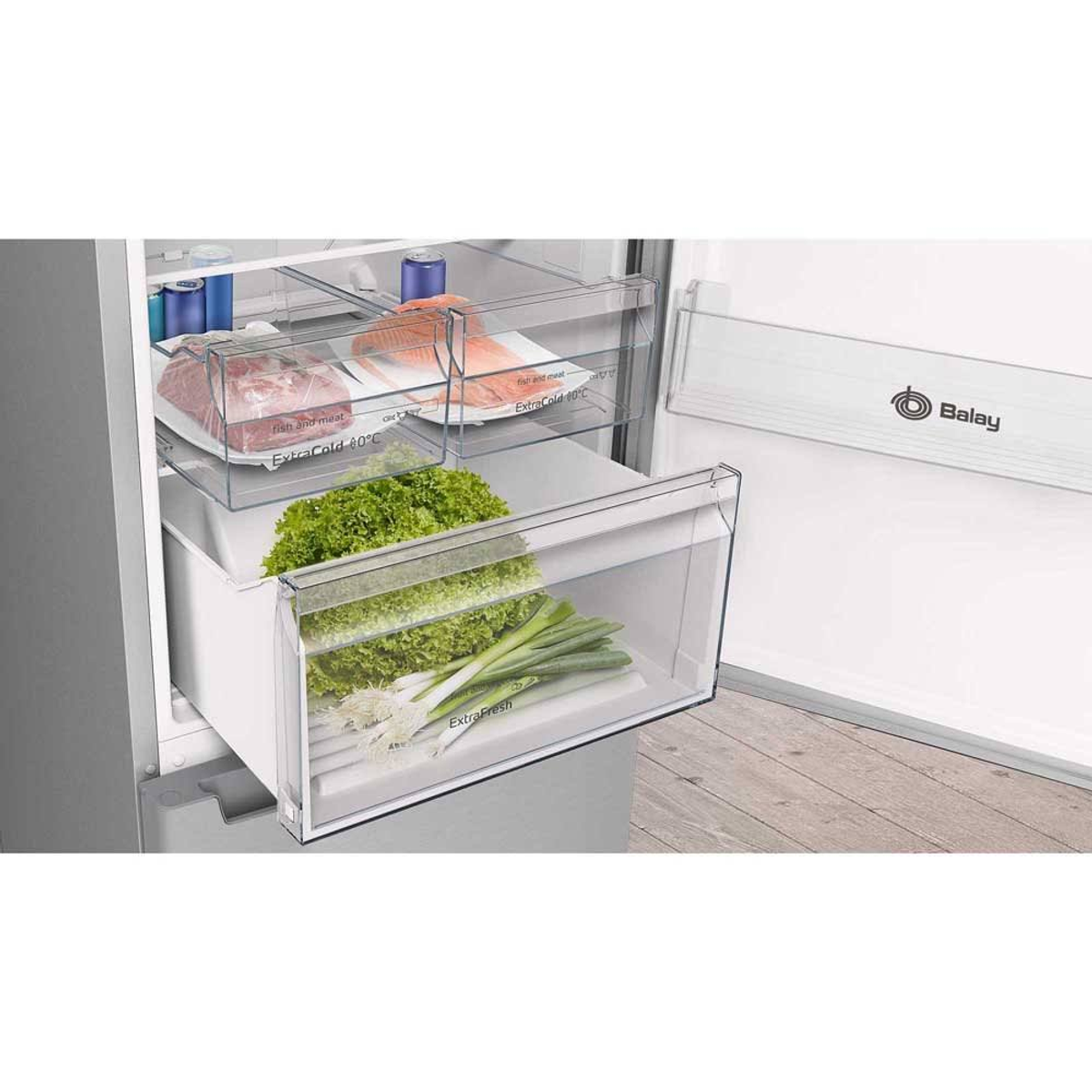 Interior de refrigerador, cajones con lechuga, cebolletas, pescado y paquetes de carne, con un logo "Balay".