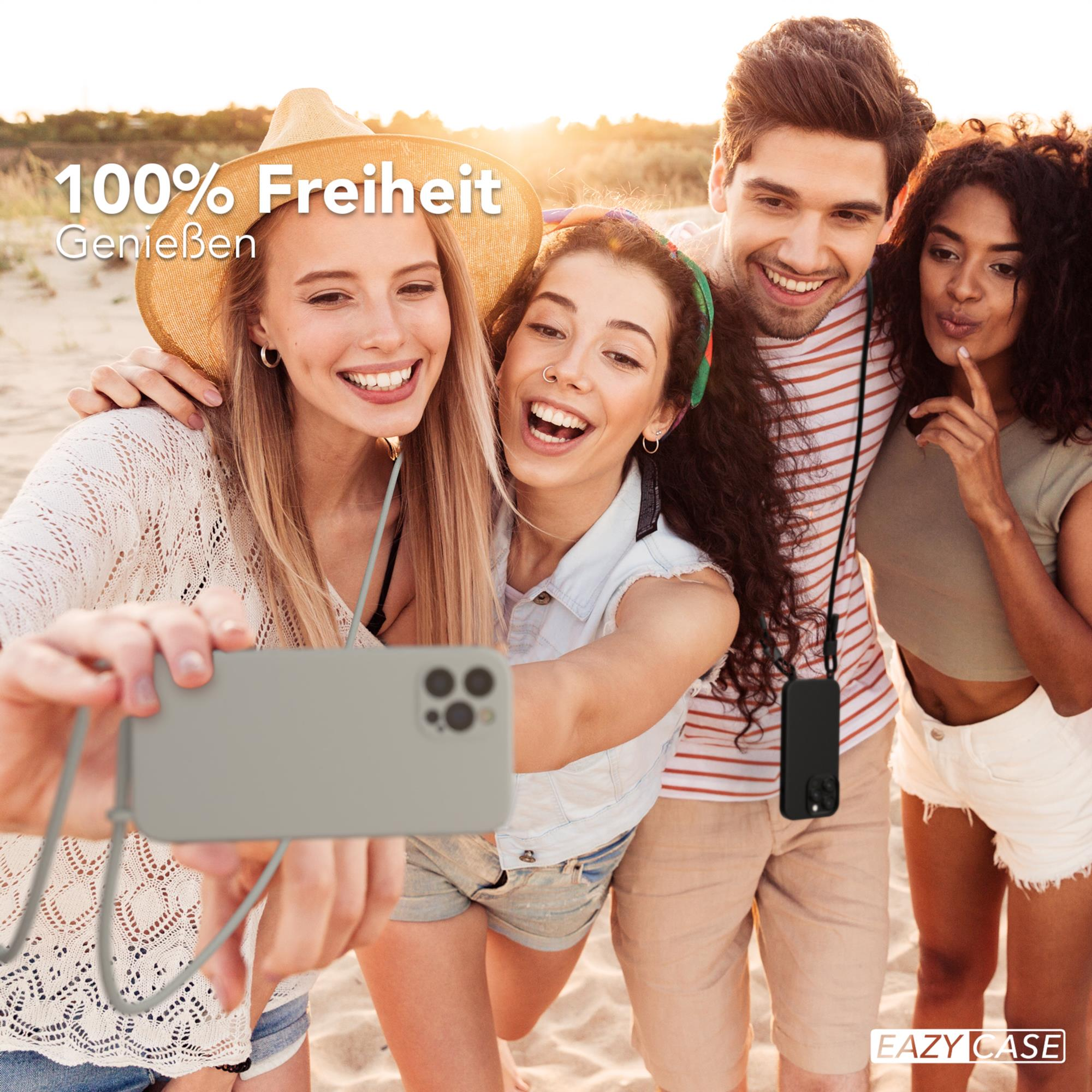 Vier Freunde machen ein Selfie am Strand, lächeln, einer trägt einen Hut.