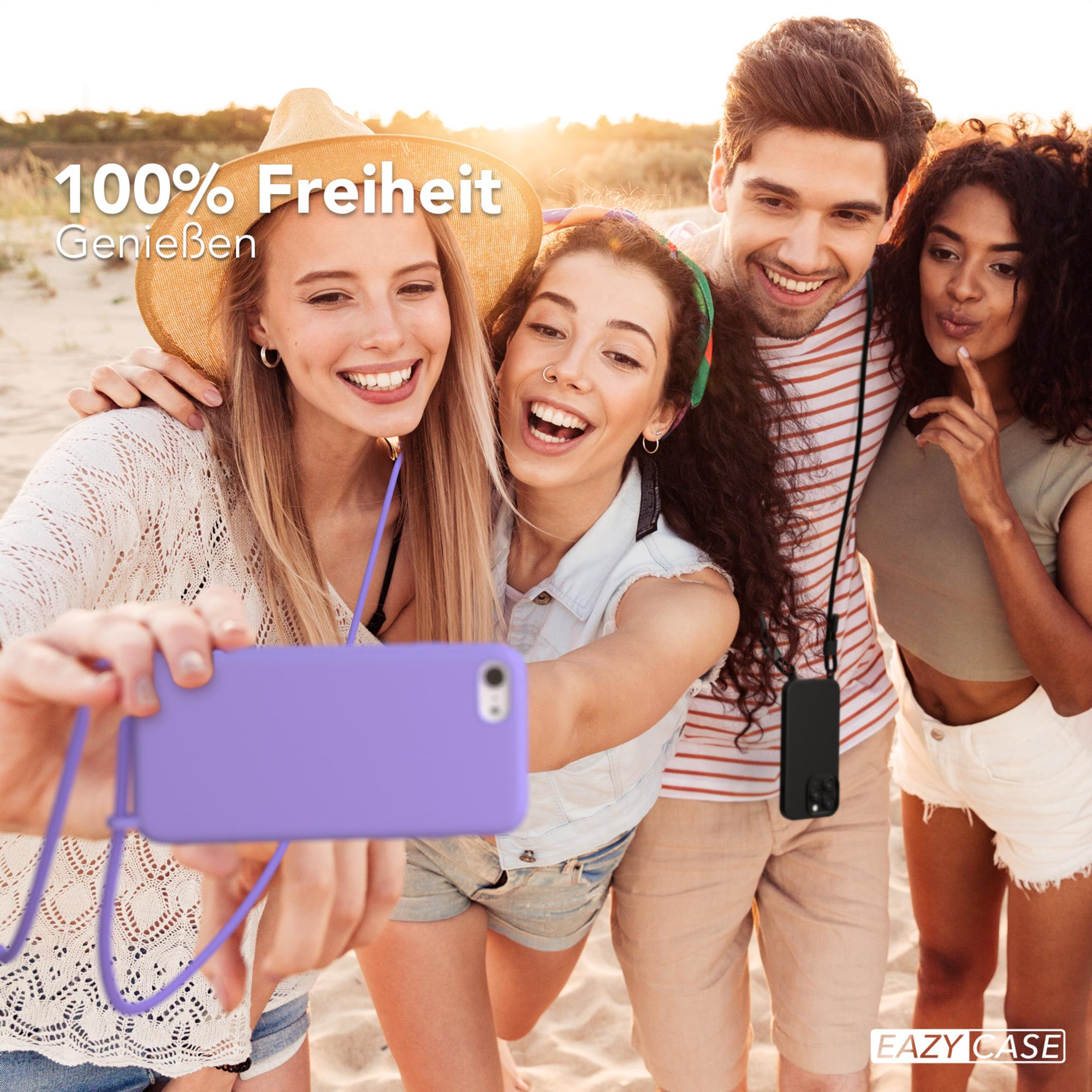 Gruppe von vier Personen macht ein Selfie mit einem lila Telefon am Strand.