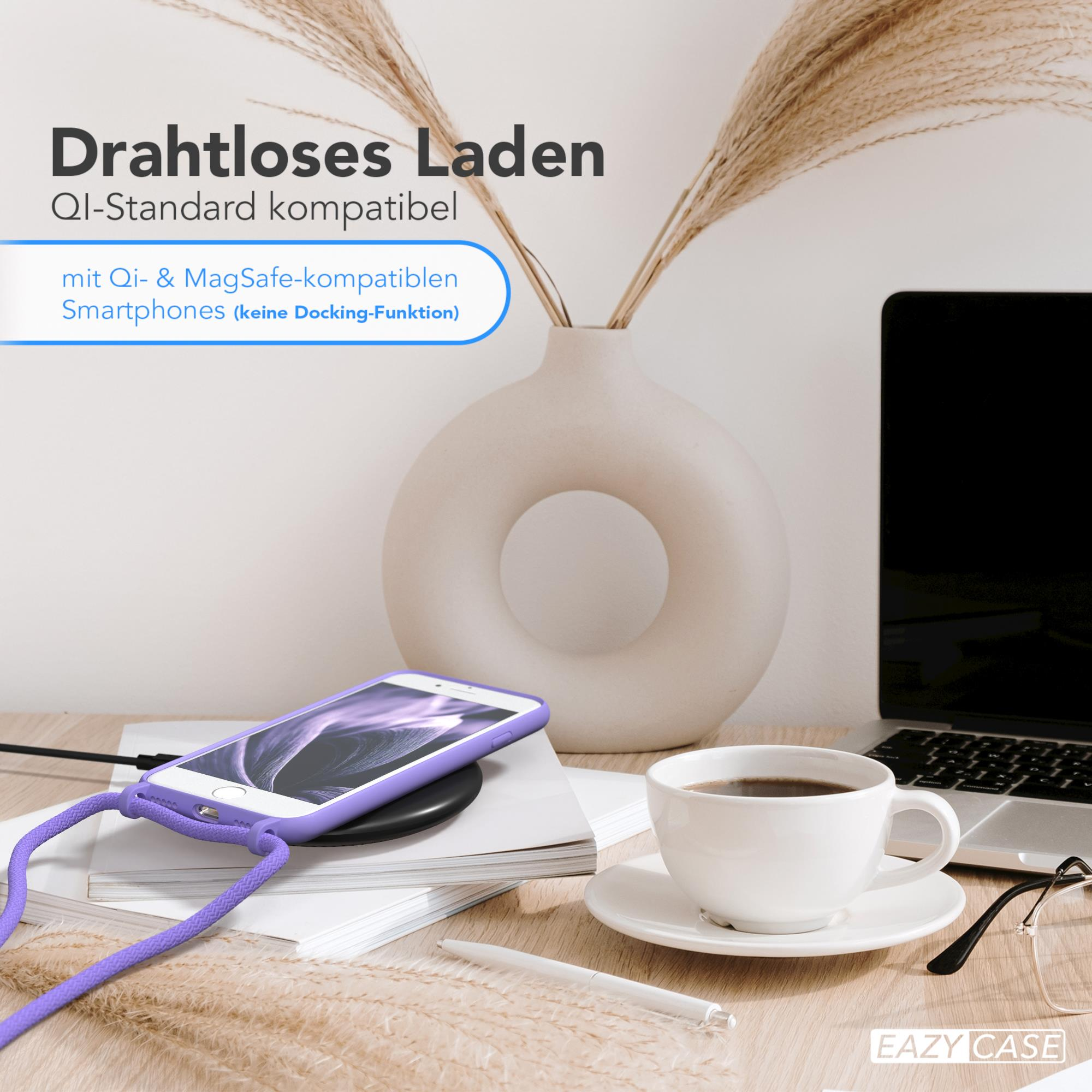 Ein Telefon lädt auf einem kabellosen Ladegerät neben einer Kaffeetasse und einem Laptop. Innenraum.