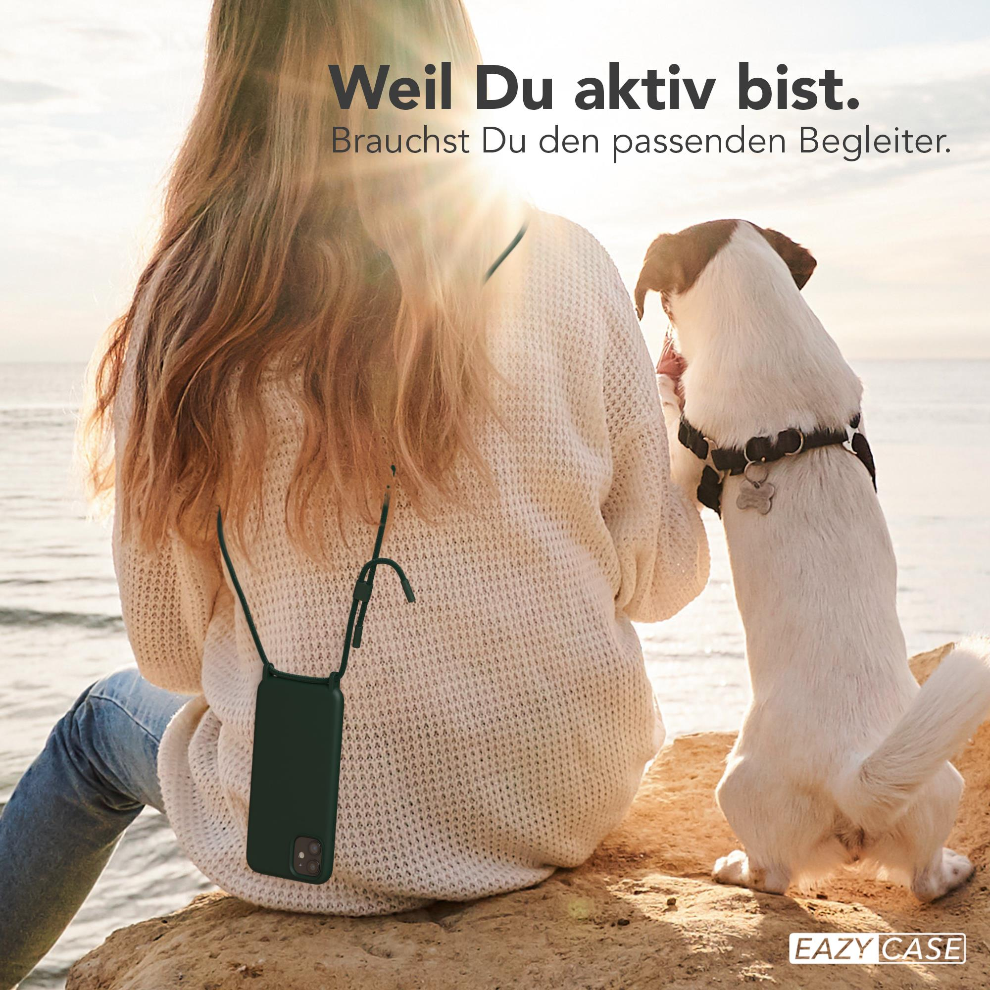 Eine Frau und ein Hund am Strand. Die Frau hält ein Telefon.