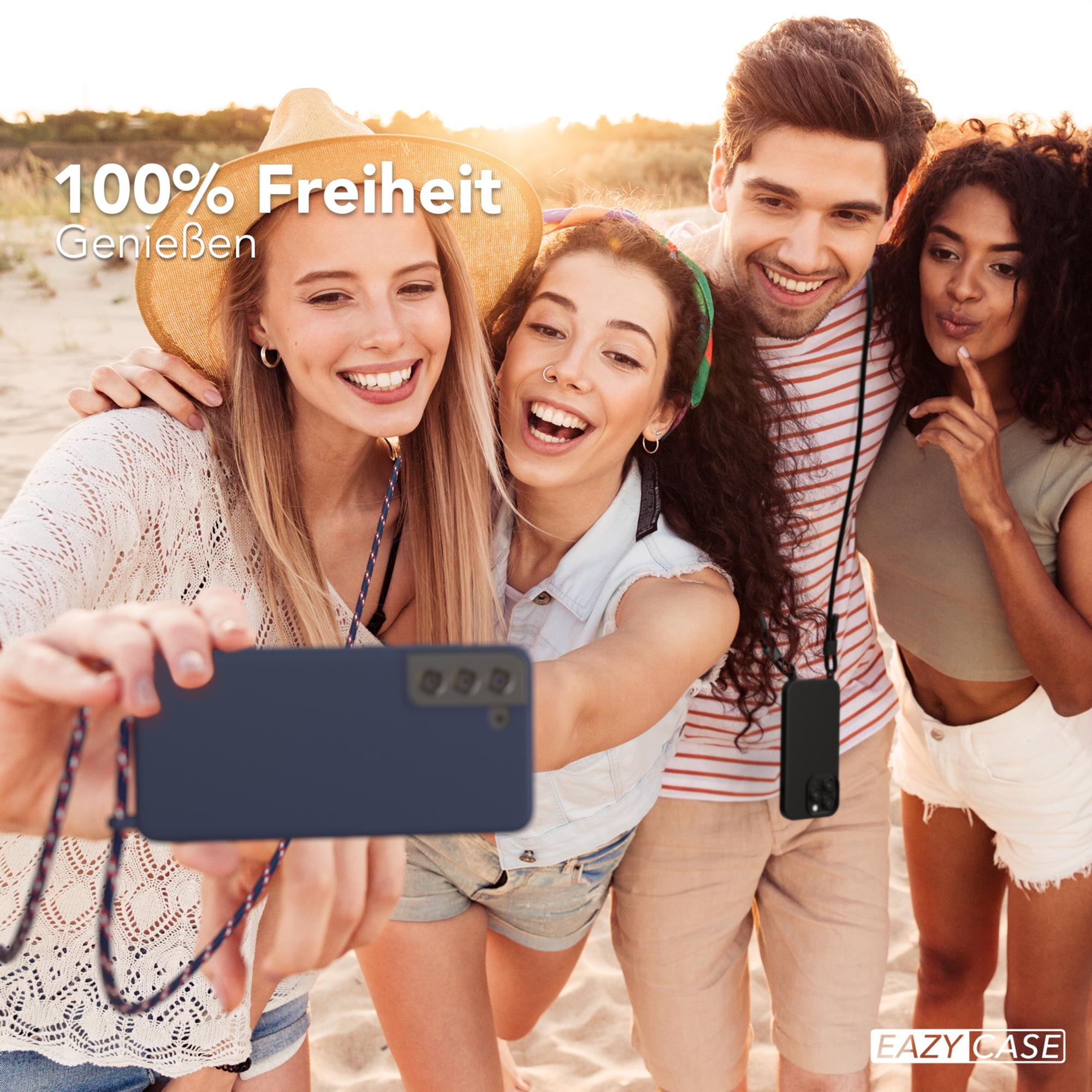 Vier Personen machen ein Selfie am Strand. Einer hält ein Telefon. Sie lächeln und sind glücklich.