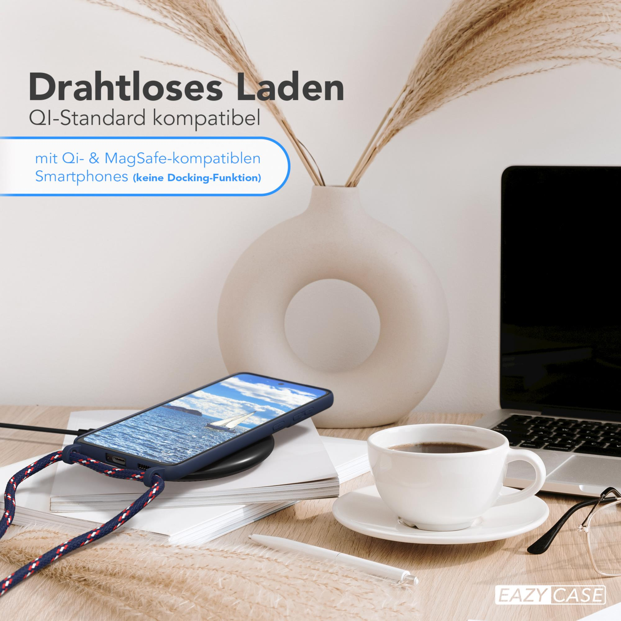 Telefon auf Ladegerät, neben Kaffeetasse und Laptop, mit Vase und Pflanze im Hintergrund.