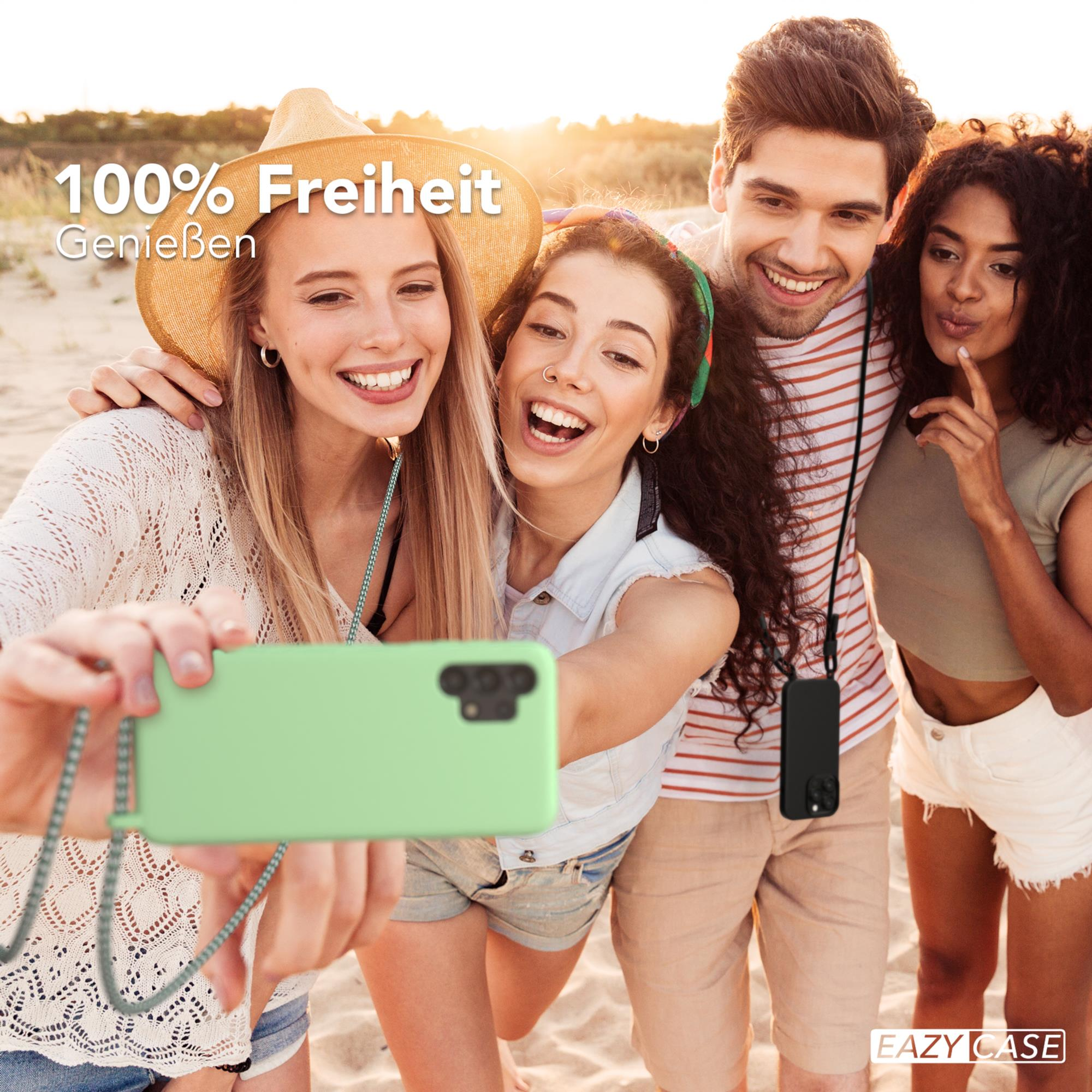 Vier Personen machen ein Selfie am Strand. Sie lächeln und halten ein Telefon mit grüner Hülle.