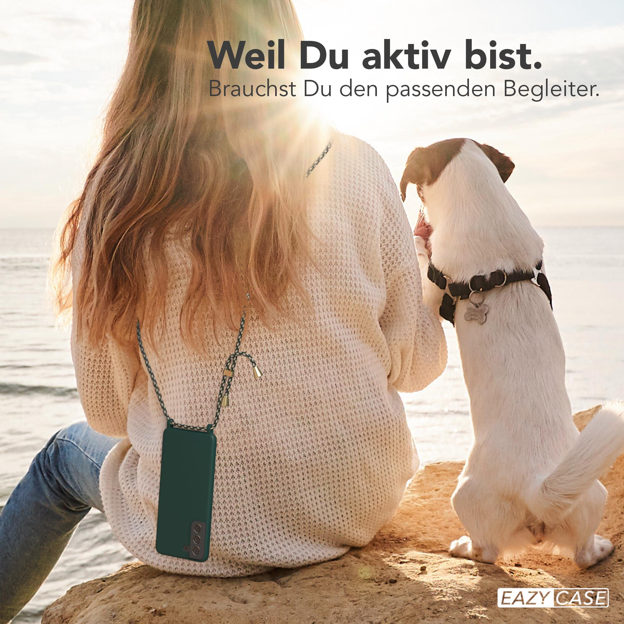 Frau mit Handyhülle auf Felsen, Hund, Ozean im Hintergrund.