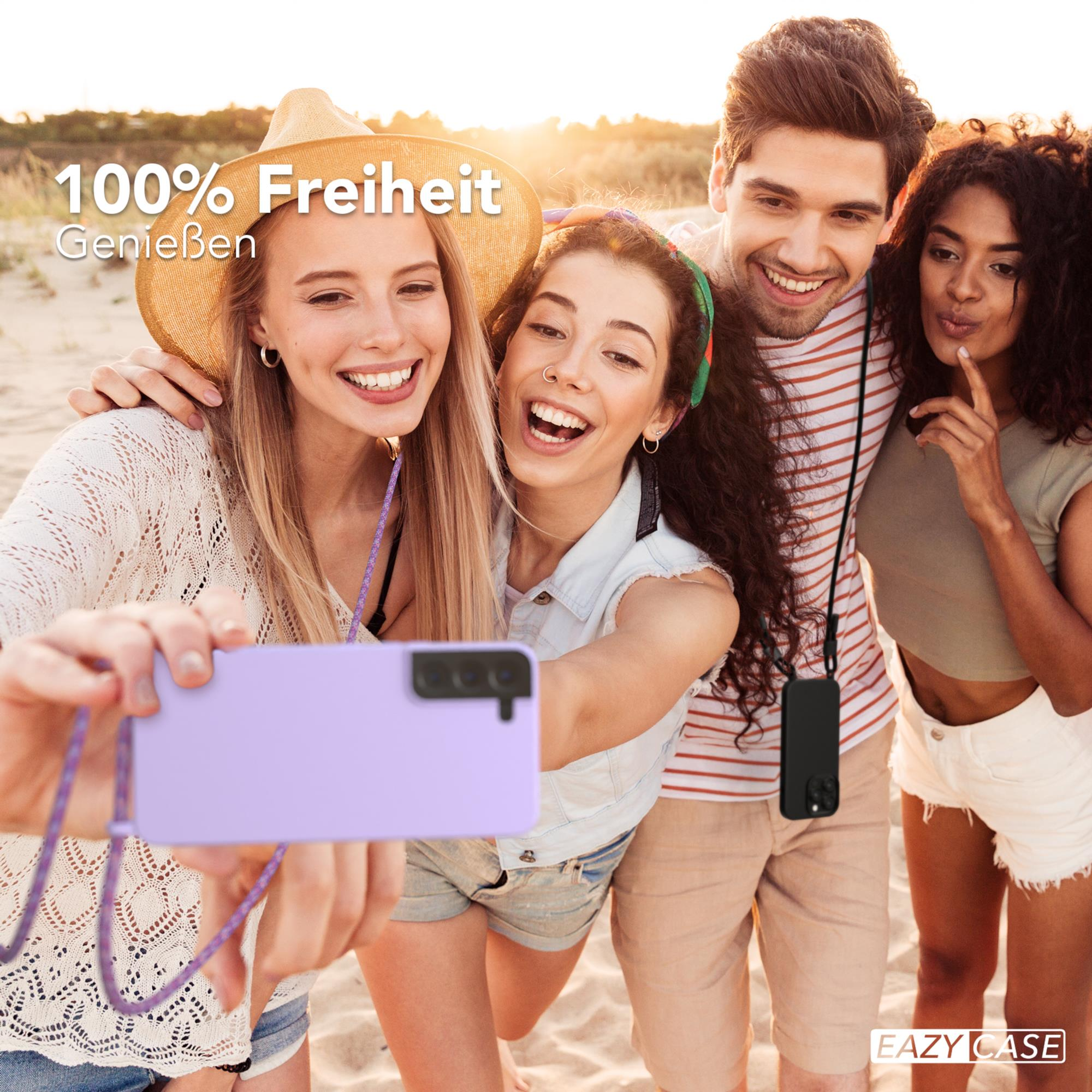 Freundesgruppe macht Selfie mit lila Handyhülle am Strand.