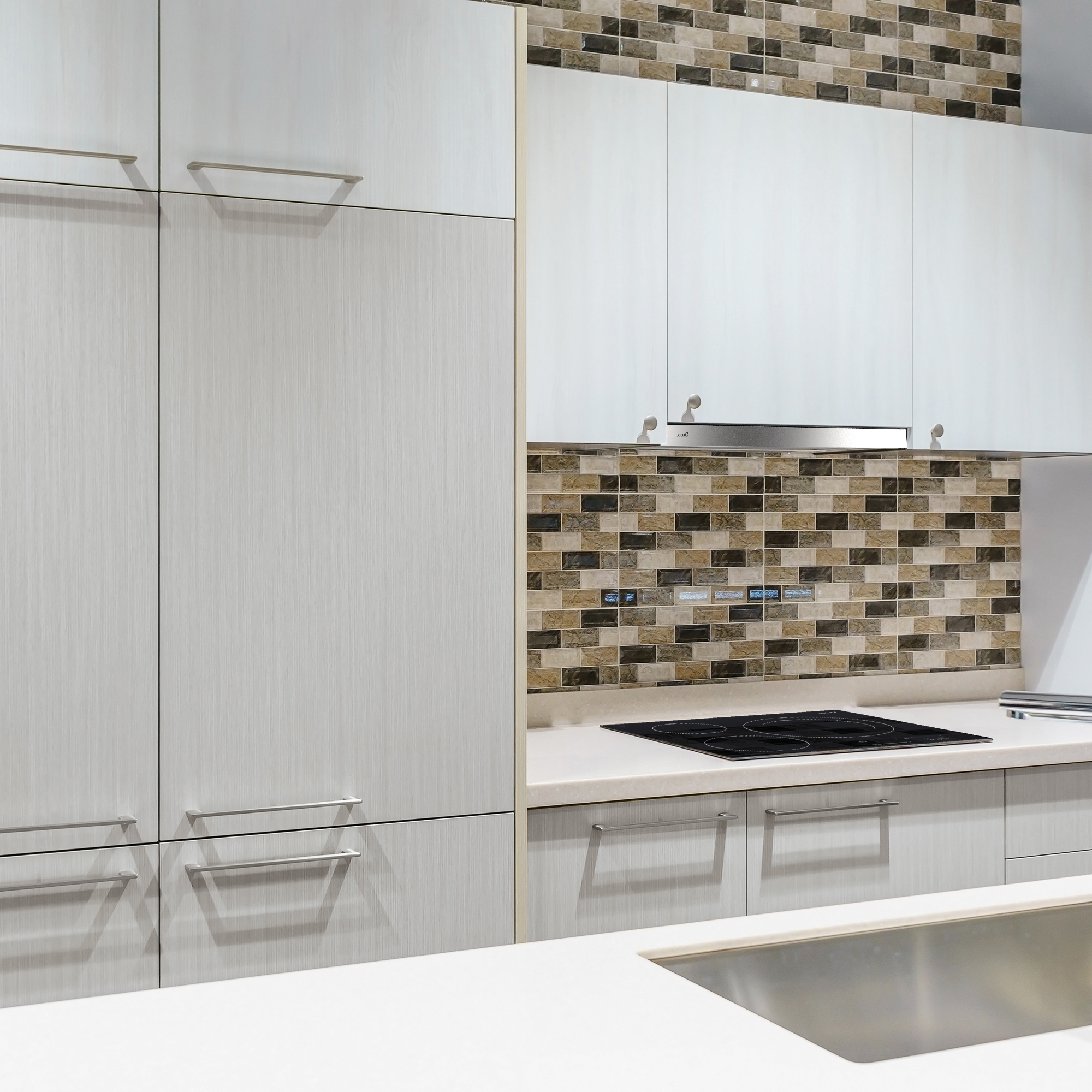 Cucina moderna con mobili bianchi, piano cottura e paraschizzi in piastrelle.