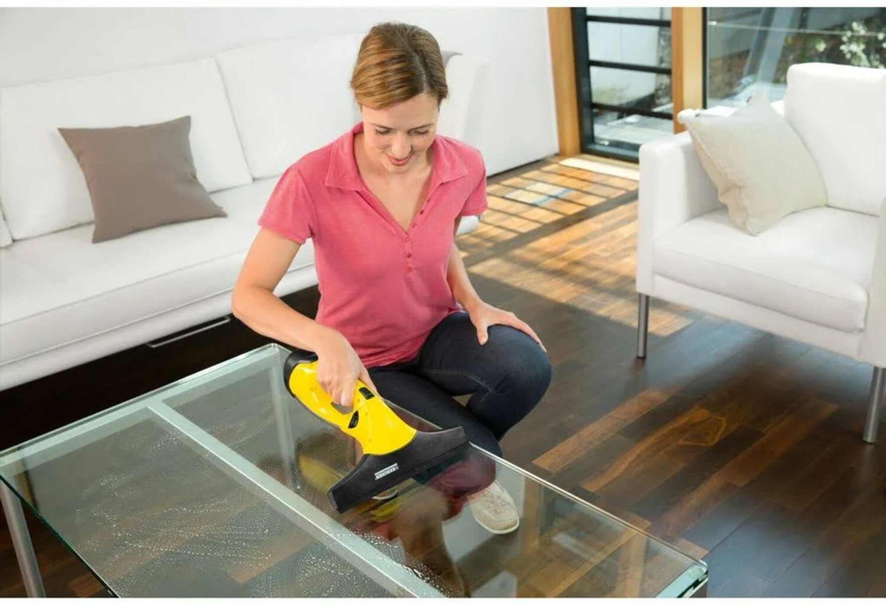 Mujer limpiando mesa de vidrio con limpiador de ventanas amarillo y negro.