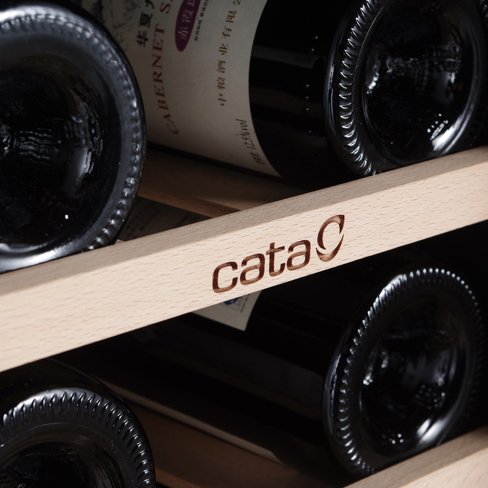 Botellas de vino en una vinoteca. El logo de Cata es visible en una estantería de madera.