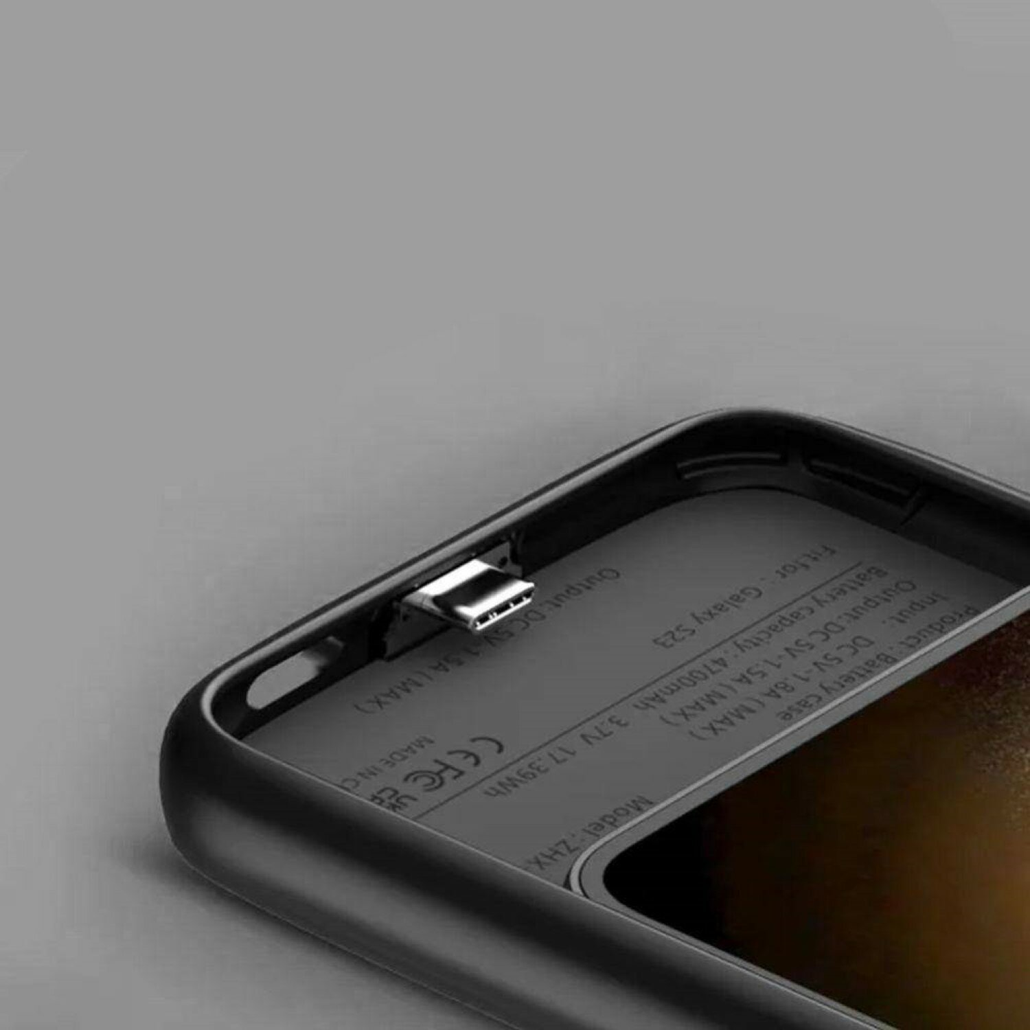 Interno della custodia del telefono nero con porta di ricarica e specifiche. Sfondo grigio.