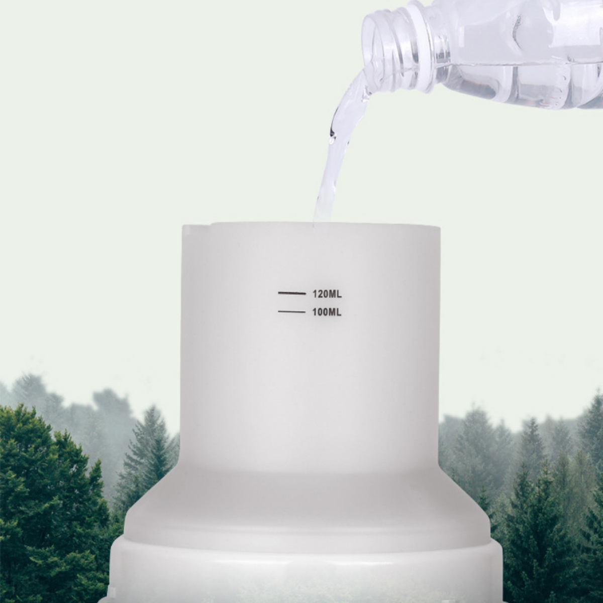 Eine Flasche gießt Wasser in einen weißen Behälter. Der Behälter hat 100ml und 120ml Markierungen.
