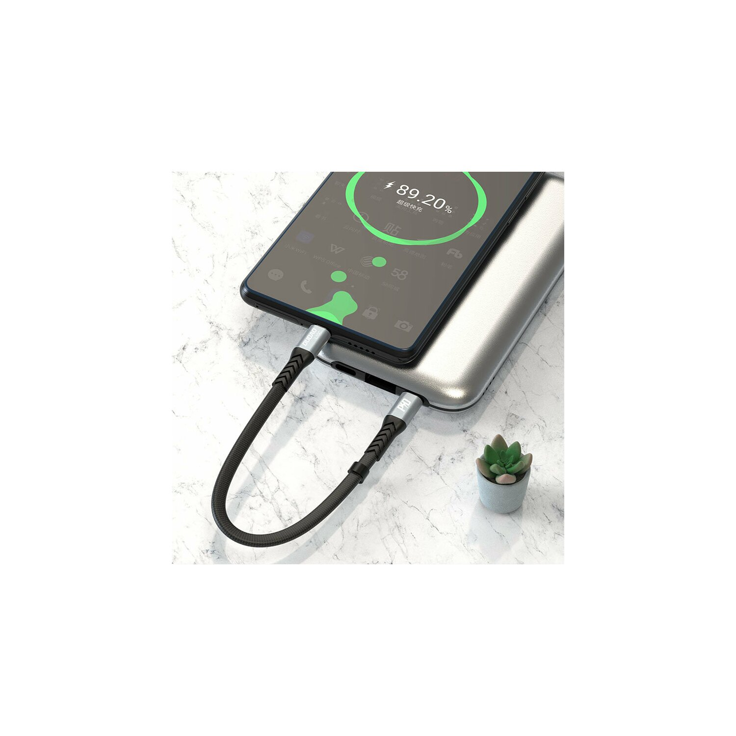 Czarny telefon ładujący srebrny power bank. Ekran pokazuje procent.