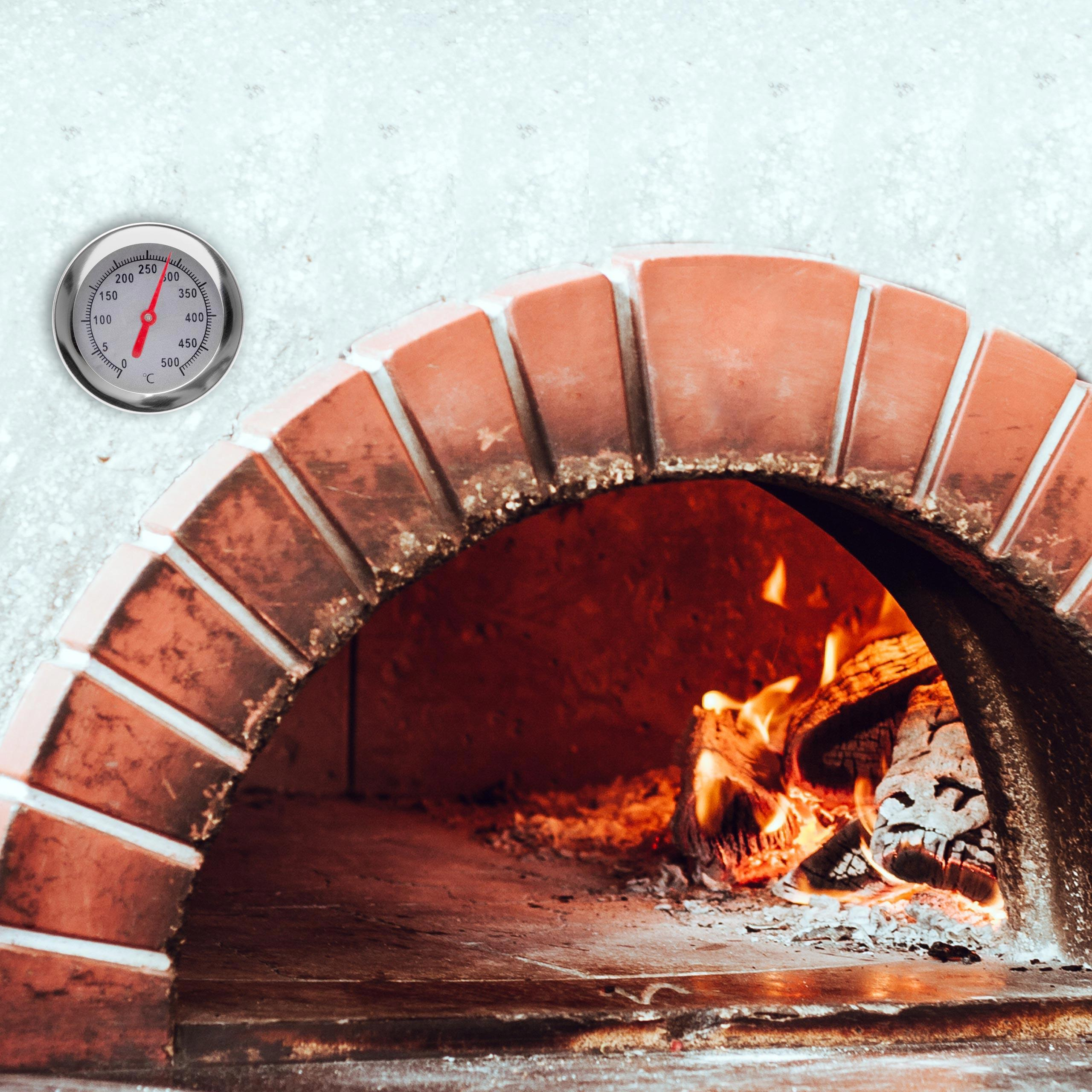 Ein Ziegelofen mit Thermometer und Feuer im Inneren. Der Ofen ist rot und gewölbt.