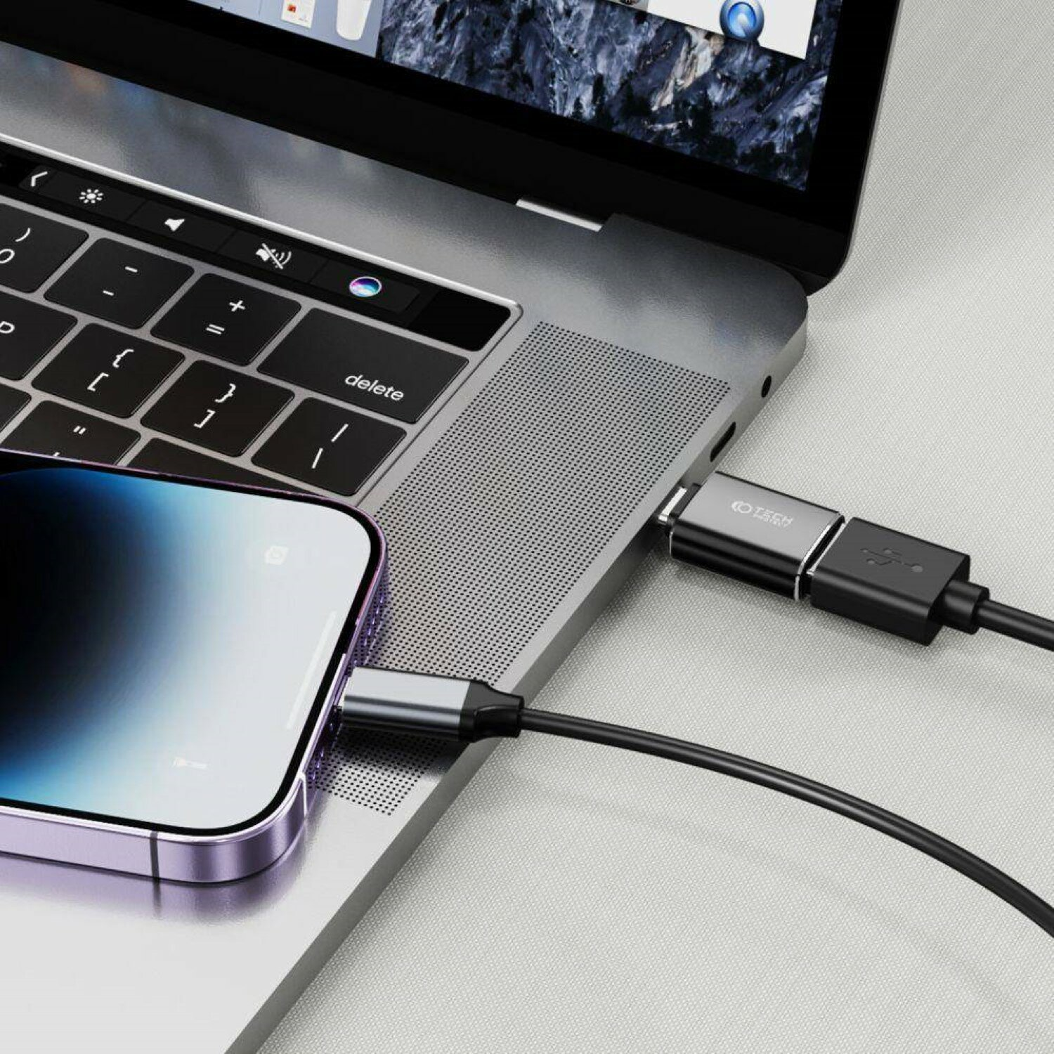 Ein Laptop, der über ein schwarzes USB-C-Adapterkabel mit einem Telefon verbunden ist. Das Telefon ist silberfarben.