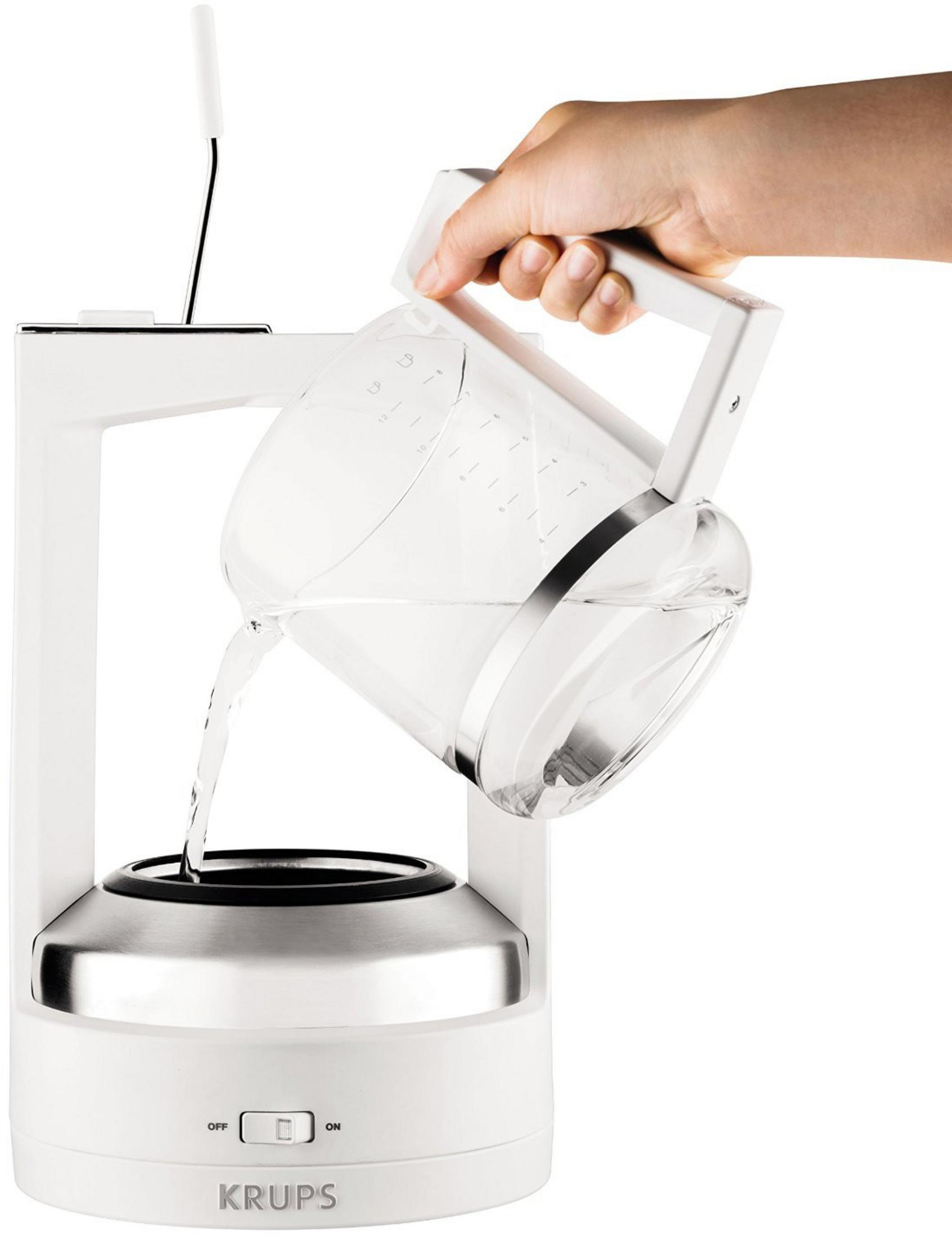 Osoba wlewa wodę z przezroczystego dzbanka do białego ekspresu do kawy.