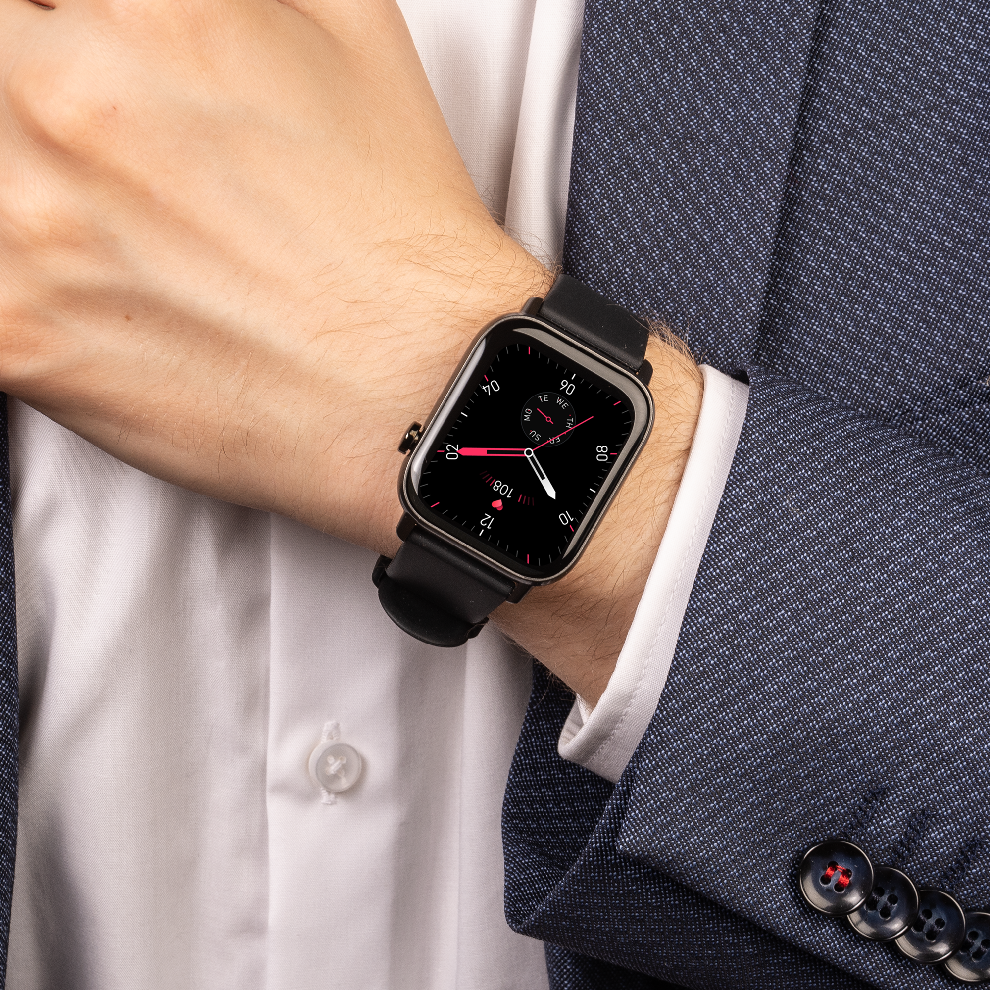 Handgelenk eines Mannes mit einer schwarzen Smartwatch auf einem blauen Blazer und weißem Hemd.