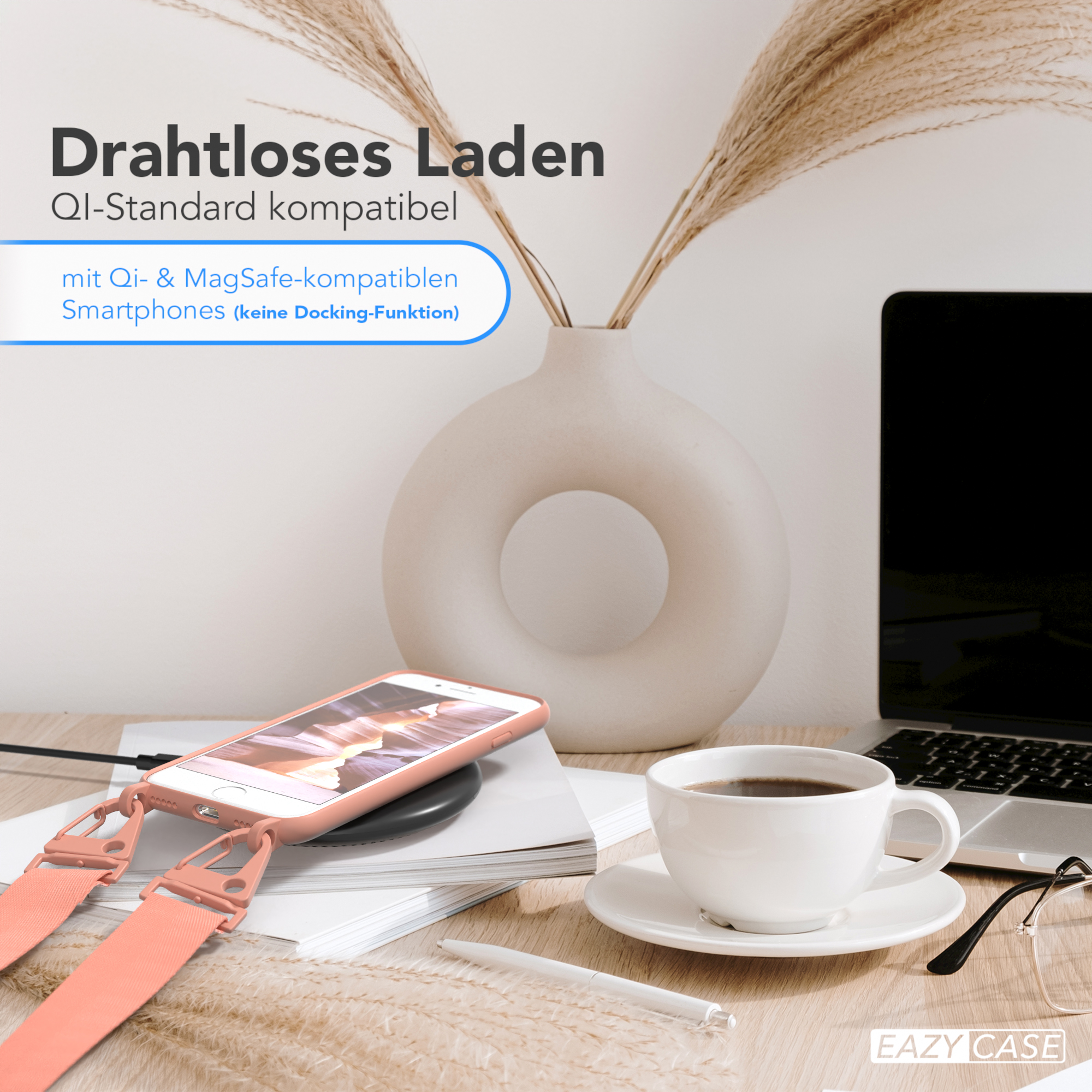 Telefon mit pinkfarbenem Band auf kabellosem Ladegerät. Kaffeetasse, Laptop und Vase im Hintergrund.