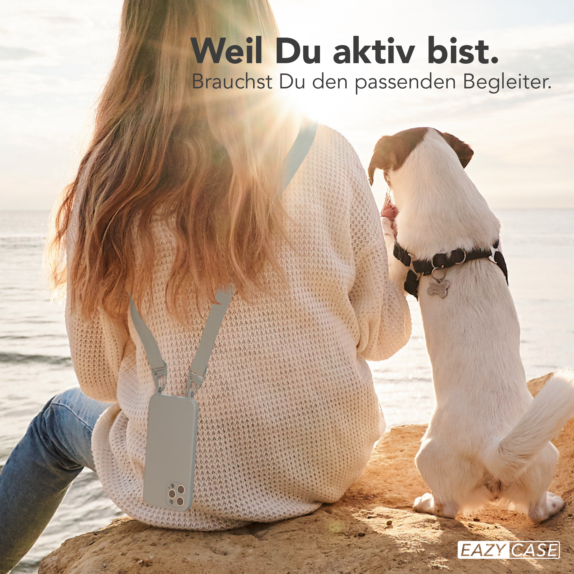 Frau mit Handyhülle und Hund an einem sonnigen Tag am Wasser.