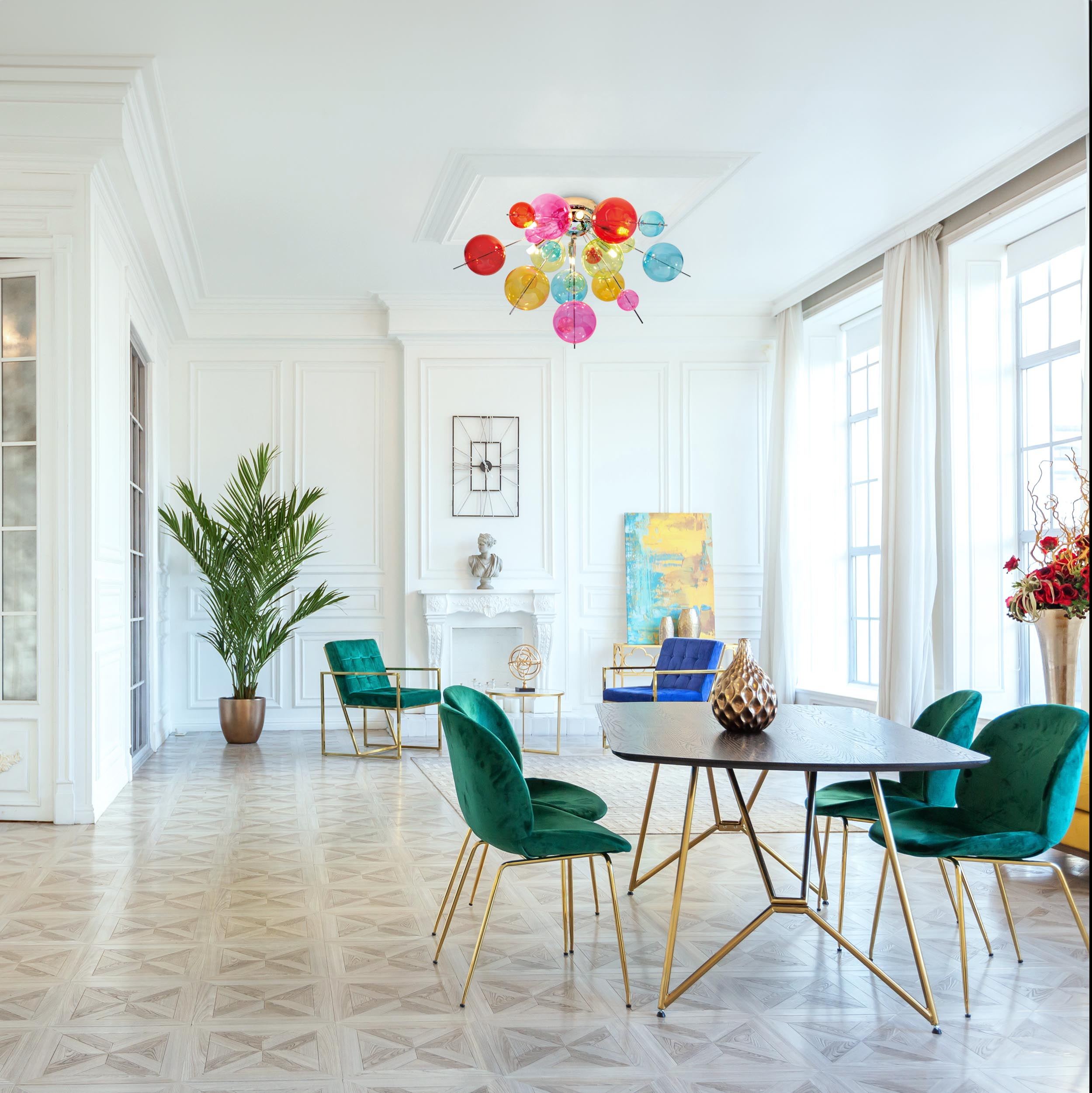 Elegantes Interieur mit farbenfrohem Kronleuchter, grünen Stühlen, Holztisch und großer Pflanze.