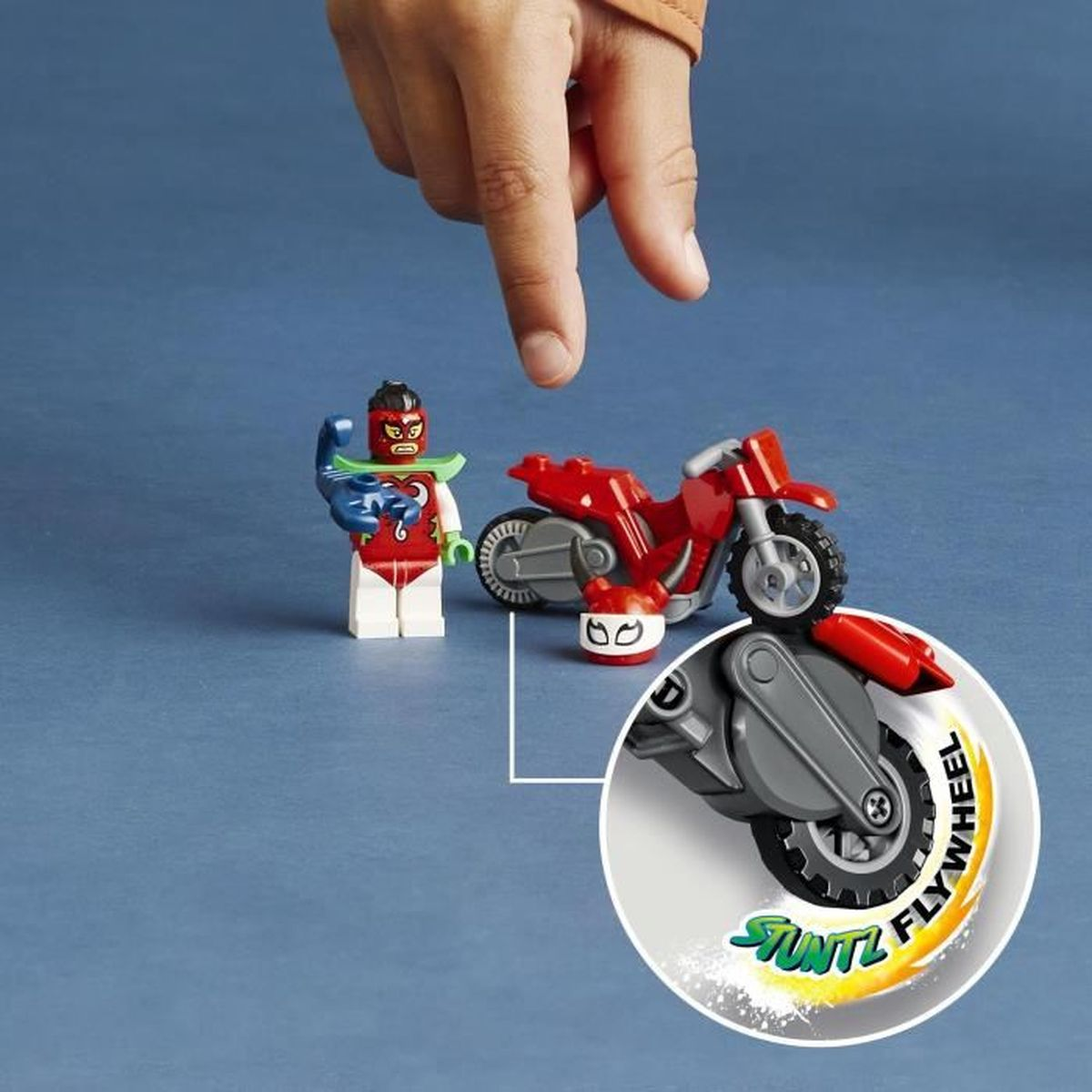 Figura de acrobacias Lego y motocicleta roja con detalle de volante, un dedo apunta.