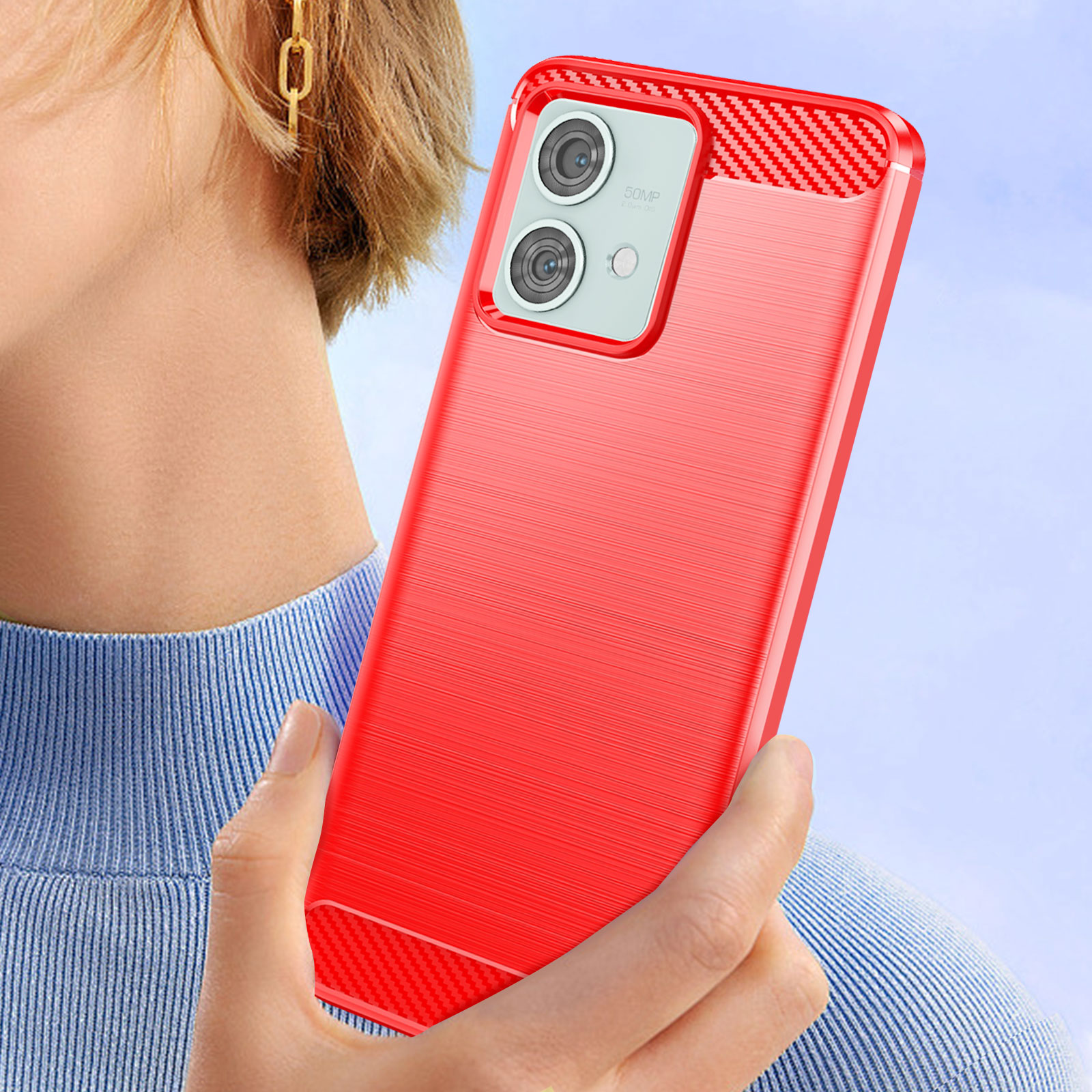 Una persona tiene in mano una custodia rossa per telefono con un ritaglio per doppia fotocamera. Uno sfondo blu.