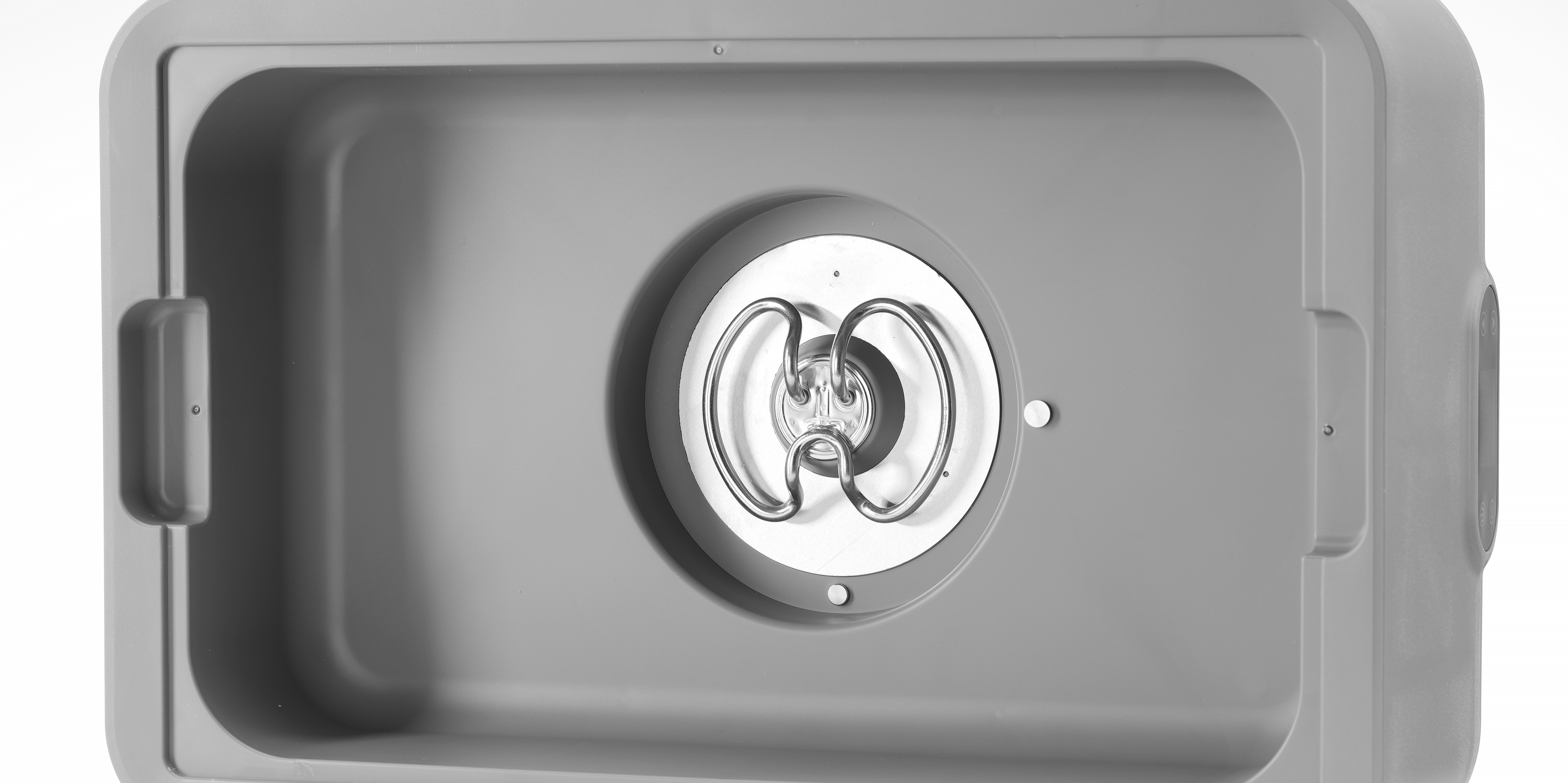 Inneres eines grauen Ultraschallreinigers. Ein rundes Heizelement ist sichtbar.