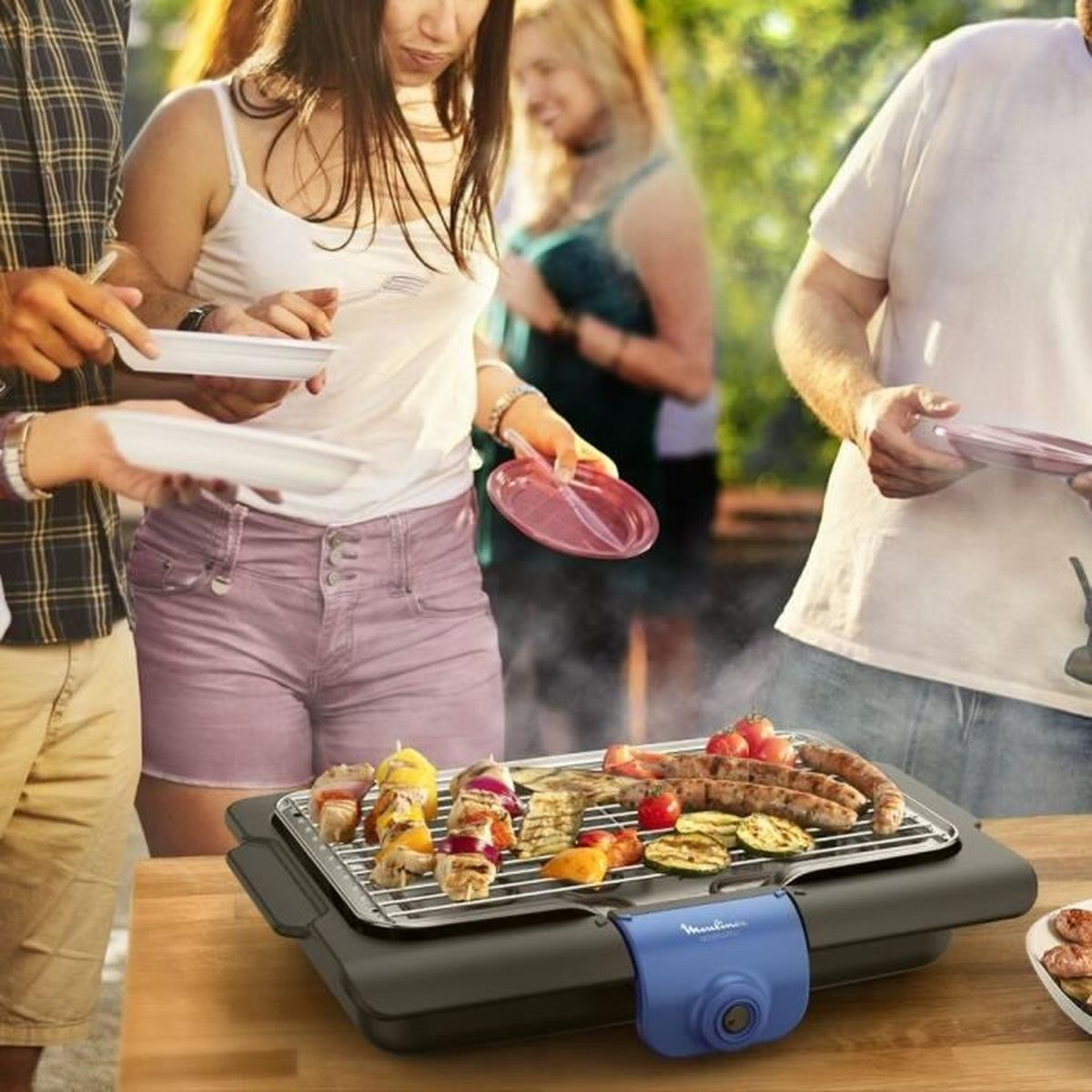 Eine Gruppe von Leuten grillt Essen auf einem Grill, mit Tellern und Beilagen.
