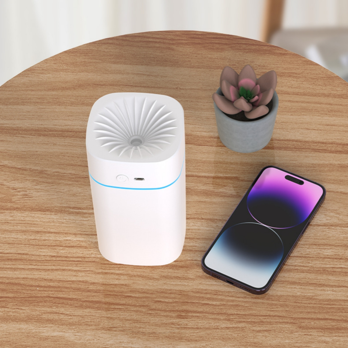 Ein weißer Diffusor und ein Telefon liegen auf einem Holztisch. Ein kleiner Blumentopf befindet sich neben dem Diffusor. Das Telefon ist an.