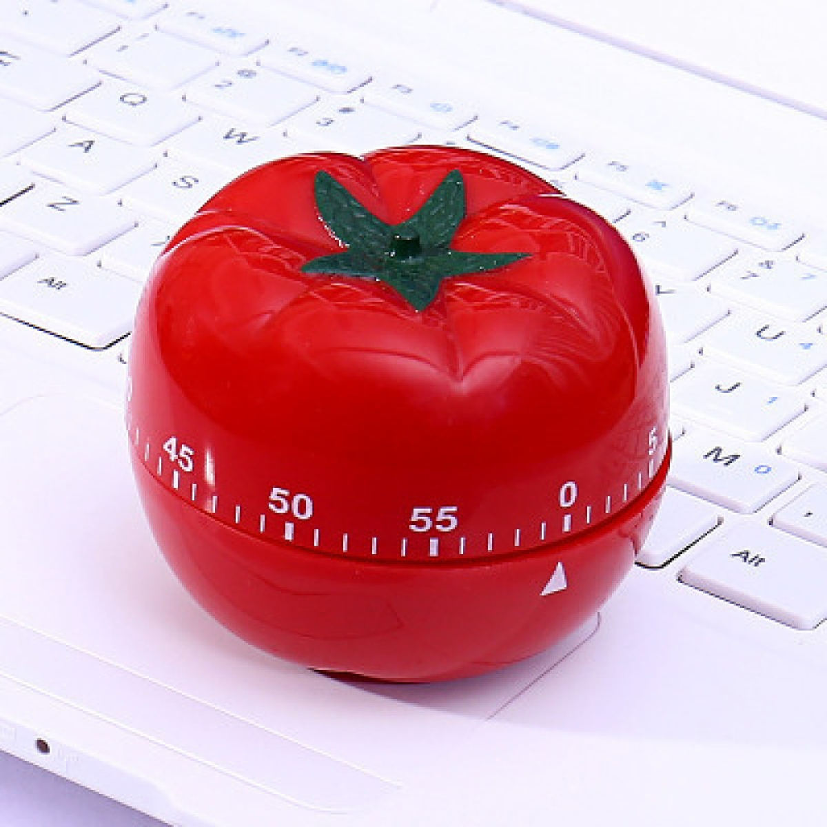 Ein roter, tomatenförmiger Küchentimer auf einer weißen Laptop-Tastatur.