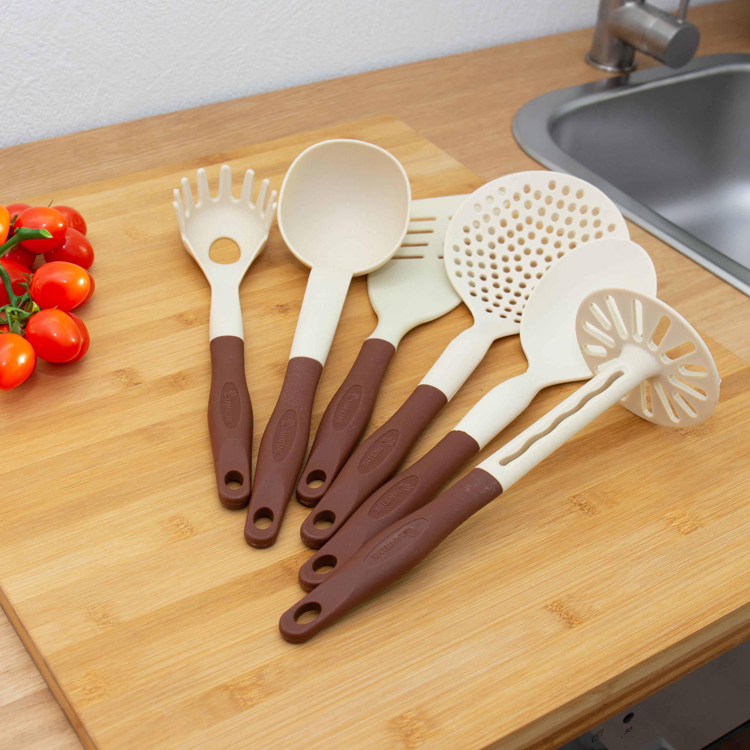 Küchenutensilien auf einem hölzernen Schneidebrett: eine Spaghettigabel, ein Löffel, ein Spatel und ein Schöpflöffel.