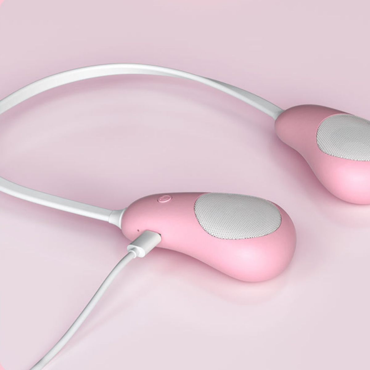 Pinkfarbener Nackenbügel-Lautsprecher mit Ladekabel auf pinkfarbenem Hintergrund.