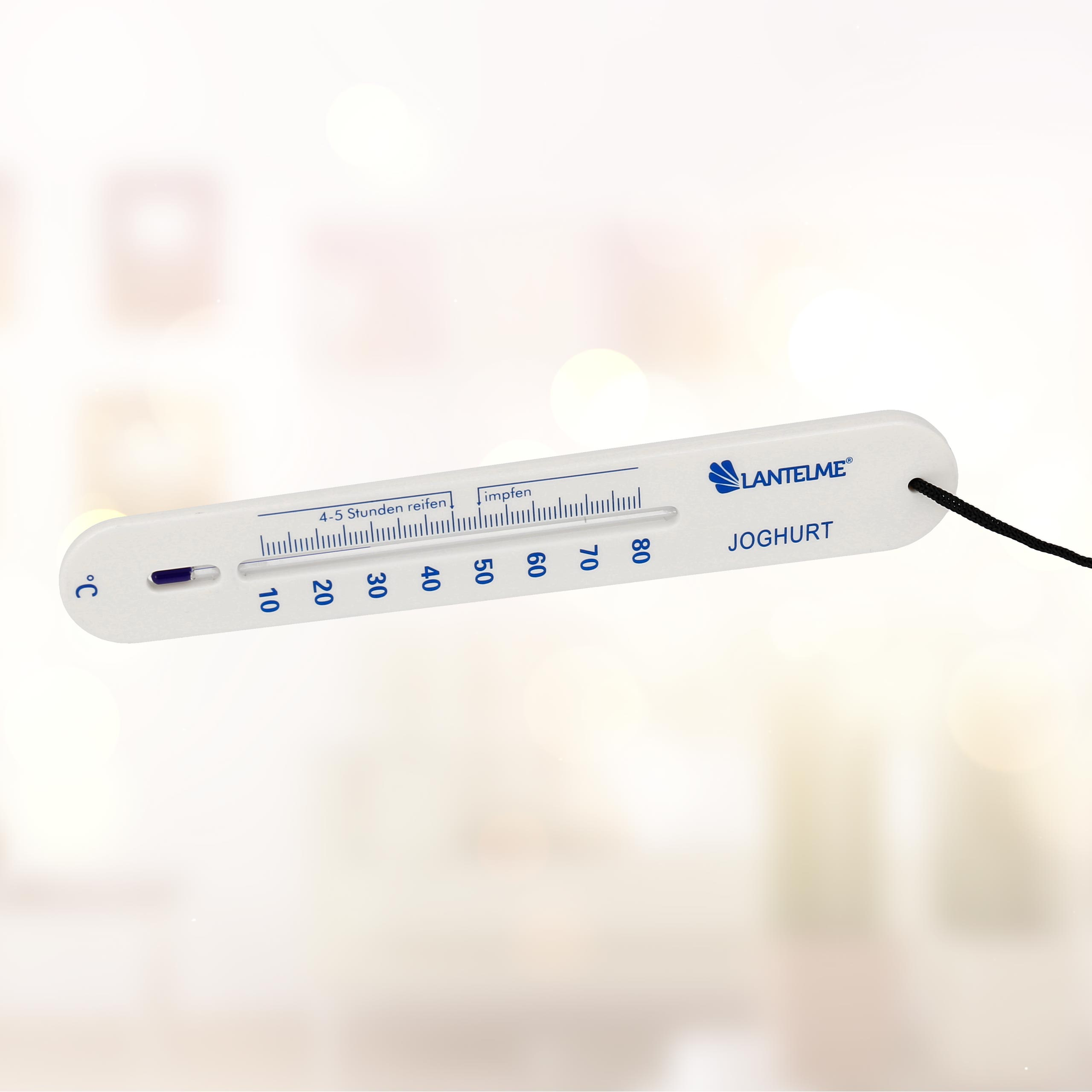 Ein weißes Thermometer mit schwarzem Faden zur Messung der Joghurt-Temperatur. Es hat eine Skala.