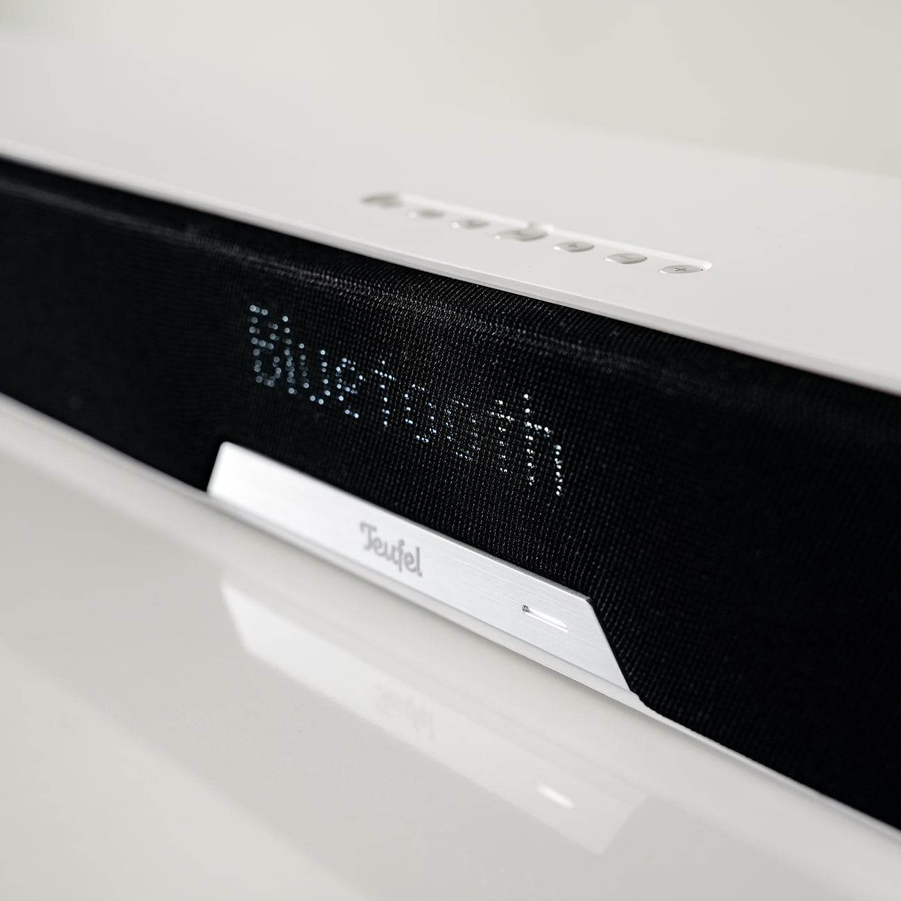 Weiße Soundbar mit Bluetooth-Text auf dem Bildschirm, mit der Marke Teufel.