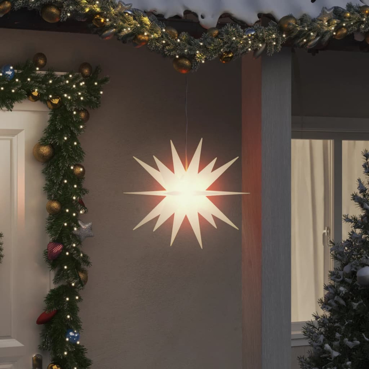 Ein beleuchteter sternförmiger Weihnachtslicht von einer Veranda hängend, mit Girlande und Baum.