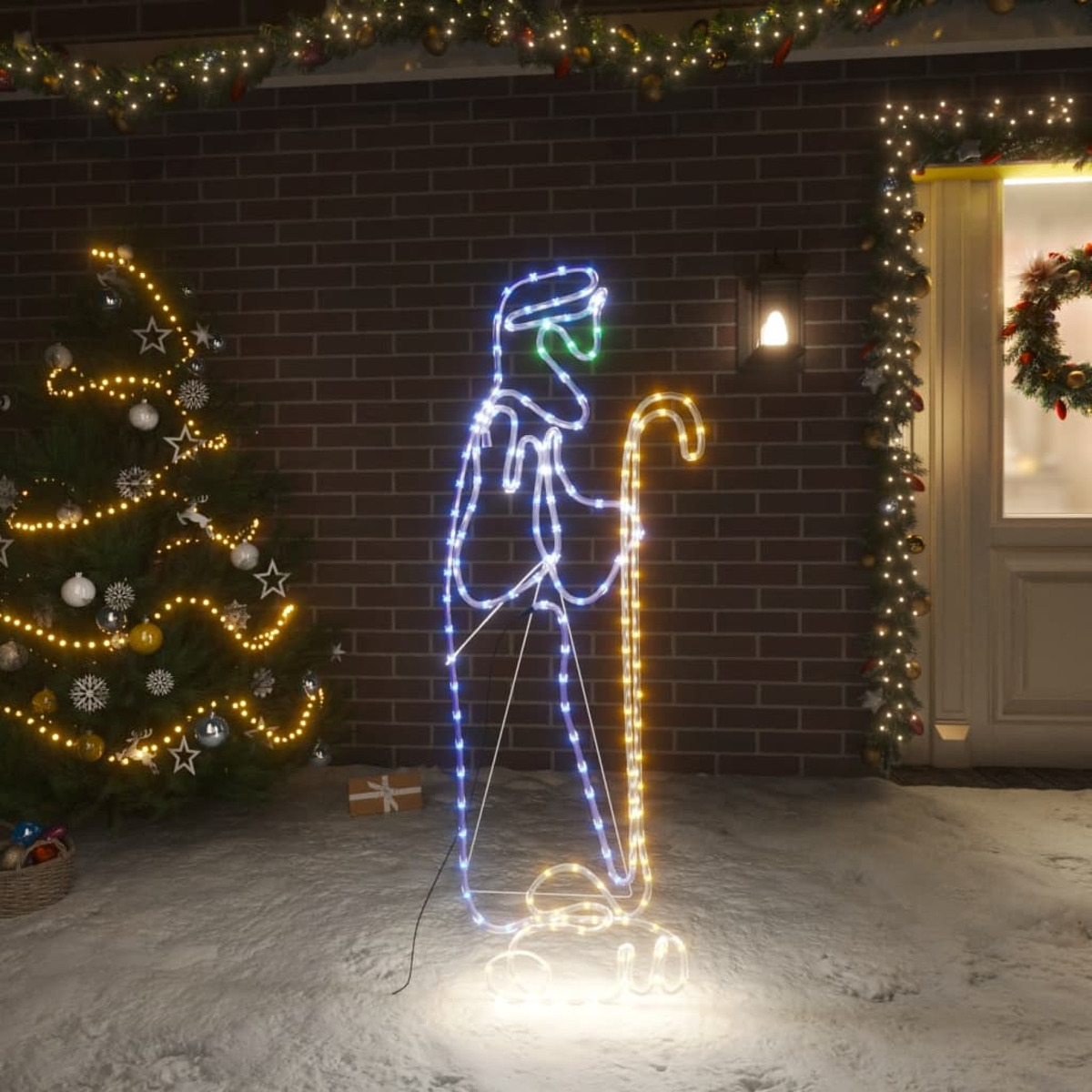 Weihnachtsbeleuchtung mit einem Mann mit Stab vor einem Haus.