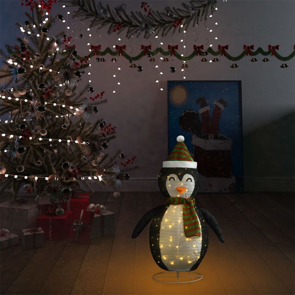 Weihnachtsdekoration Pinguin mit Lichterketten. Geschenke und Weihnachtsbaum im Hintergrund.