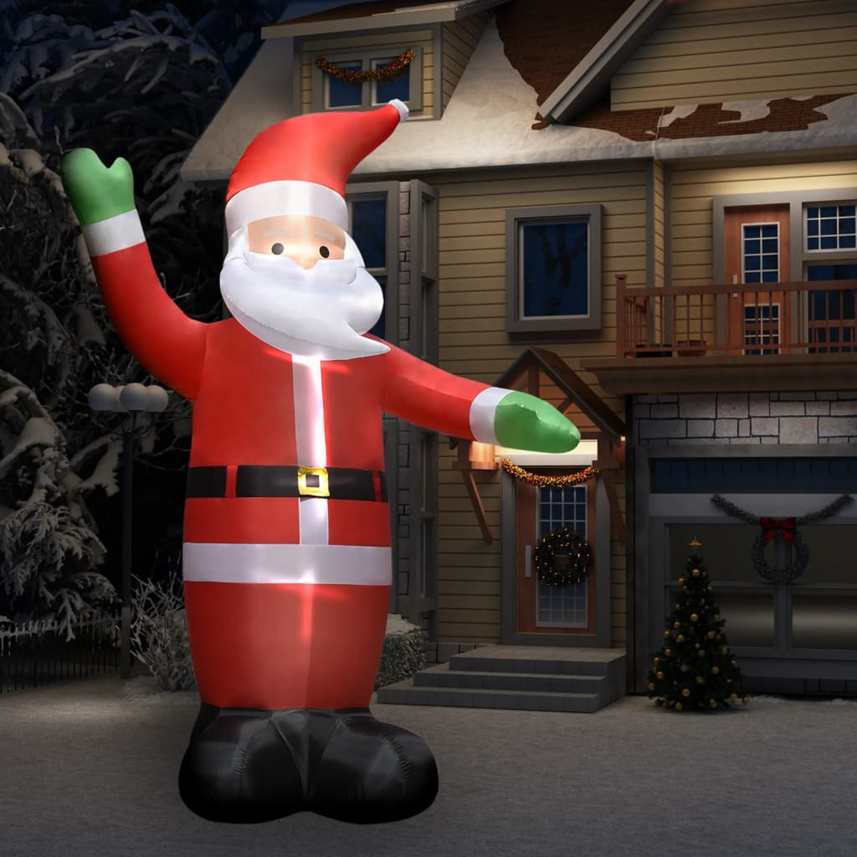 Eine aufblasbare Weihnachtsmannfigur steht nachts vor einem Haus, beleuchtet durch einen Scheinwerfer.
