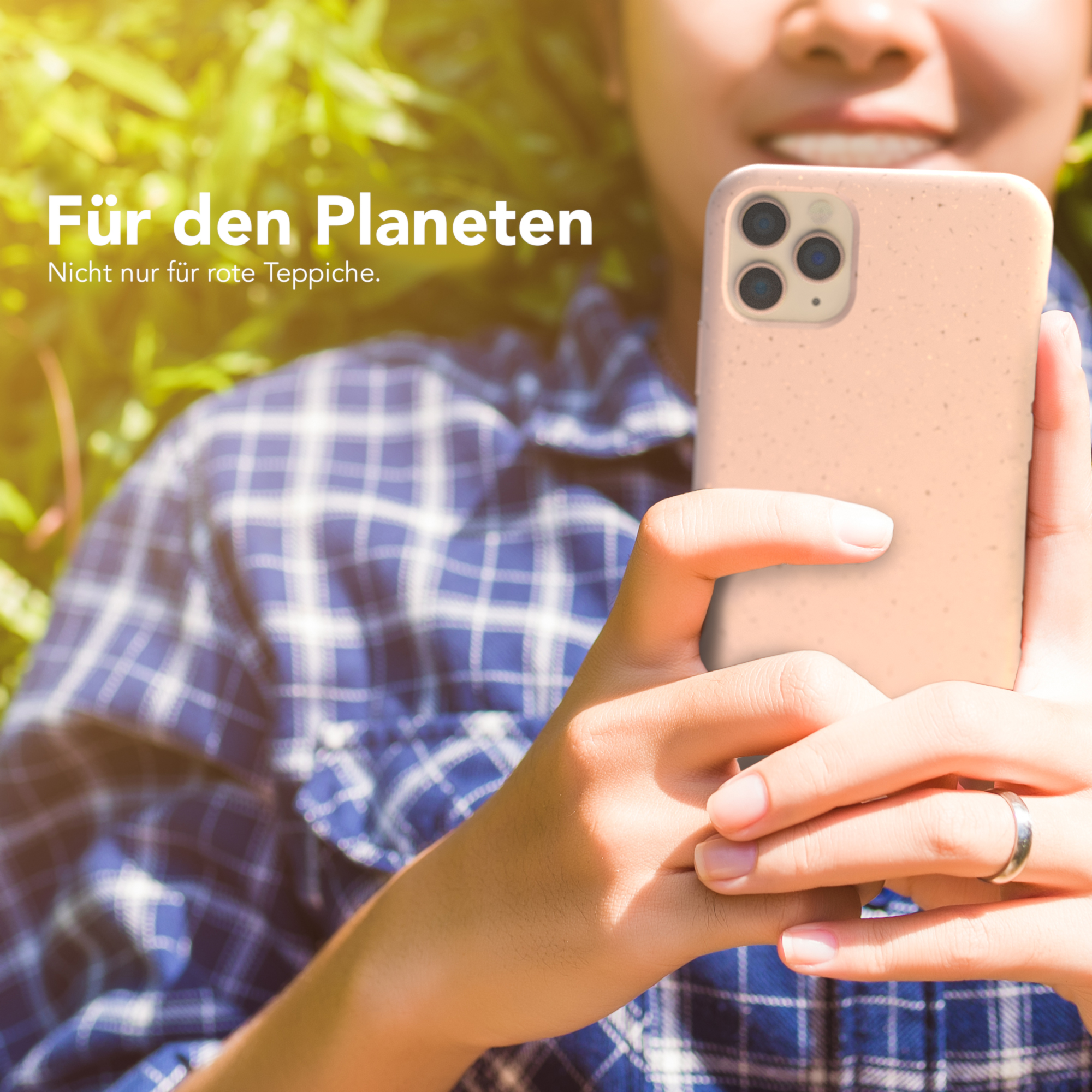 Person hält eine rosa Handyhülle vor dem Hintergrund von grünem Laub und Text.