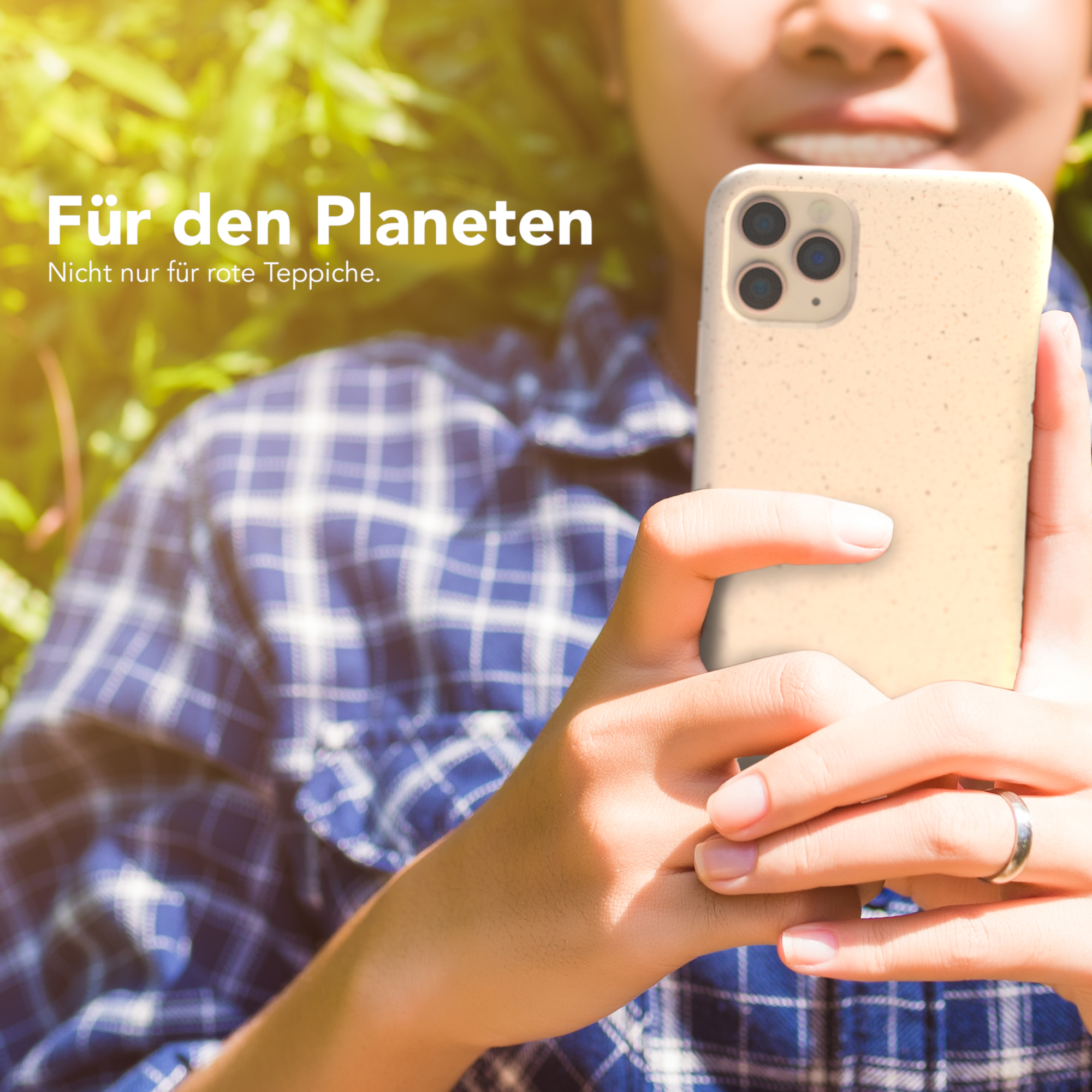 Eine Person, die eine beige Handyhülle vor grünen Blättern hält. Text sagt 'Für den Planeten'.