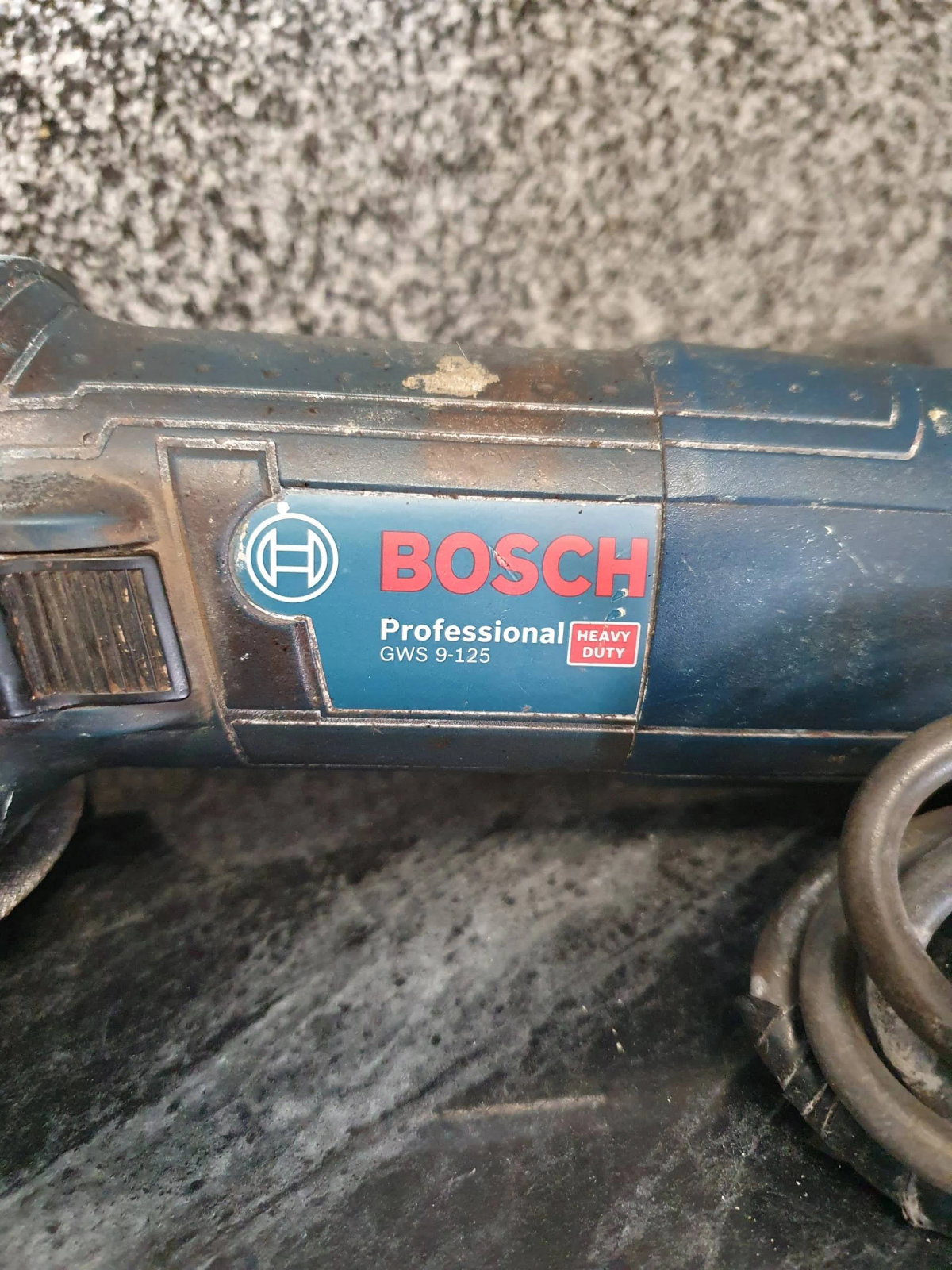 Nahaufnahme eines Bosch Professional GWS 9-125 Winkelschleifers, blau und schwarz, Rostflecken.