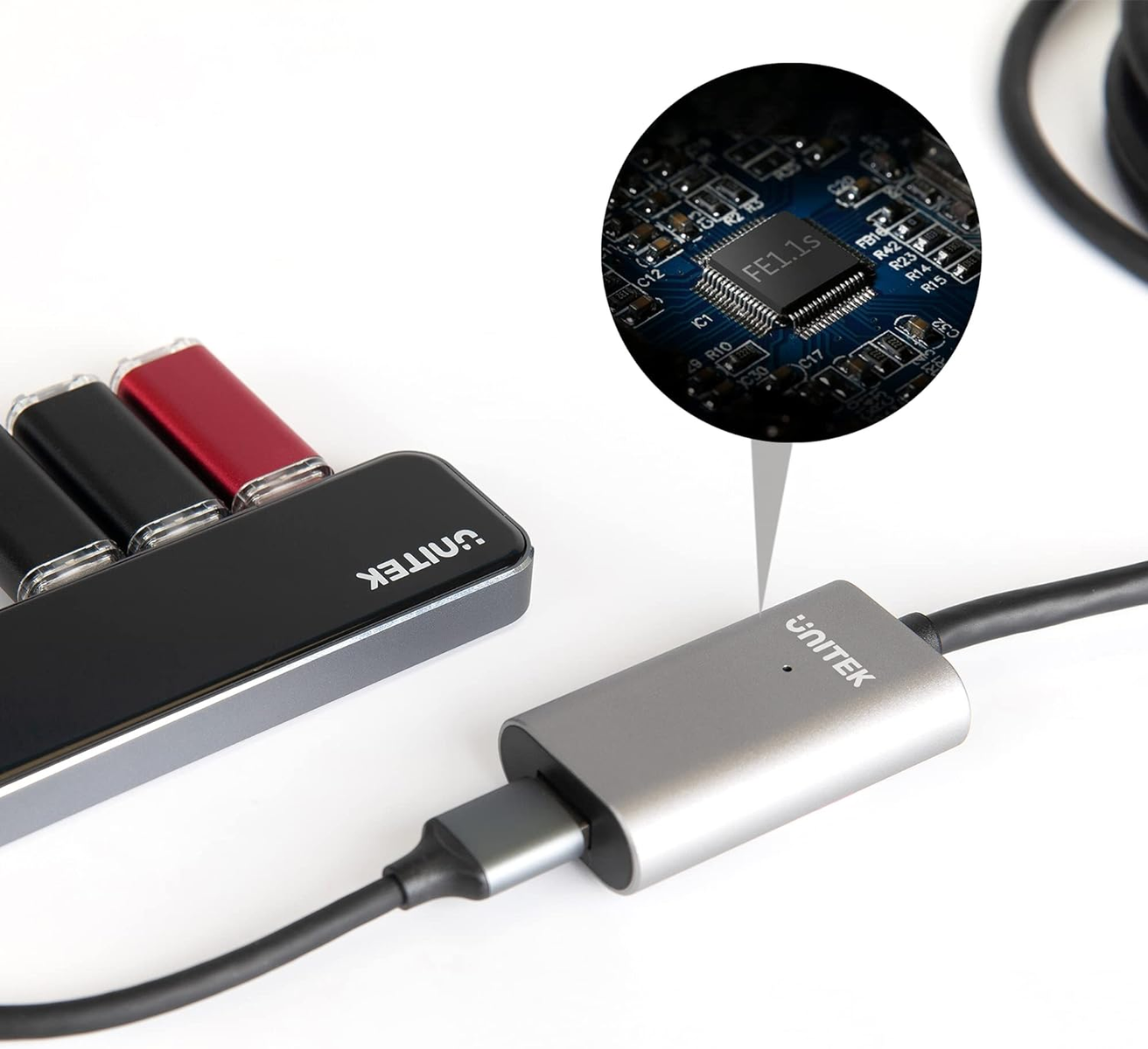 Ein schwarzer Hub mit USB-Laufwerken, ein silberner Adapter mit angeschlossenem Kabel und ein Detail der Leiterplatte.
