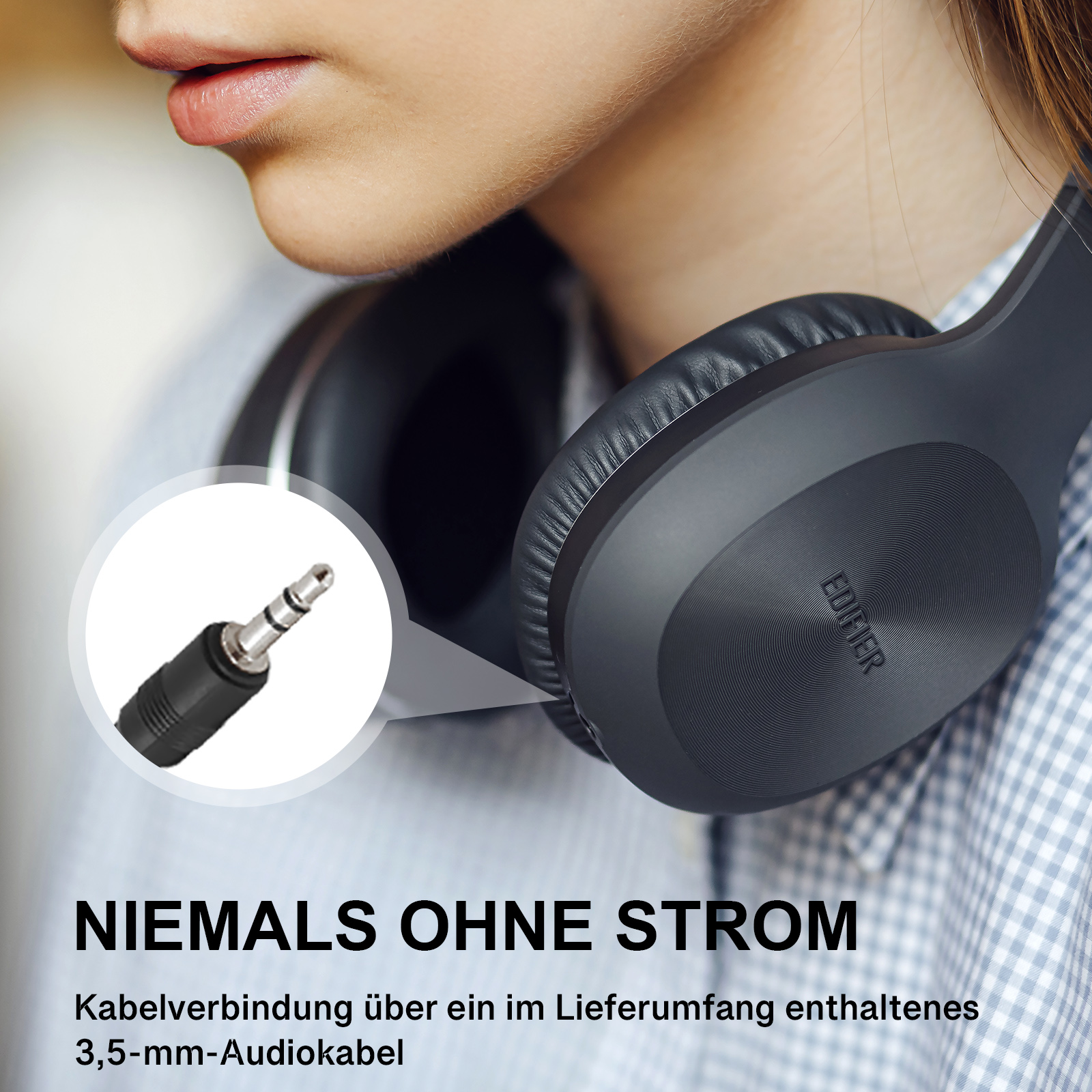 Zbliżenie osoby w ciemnoszarych słuchawkach, z kablem audio 3,5 mm.