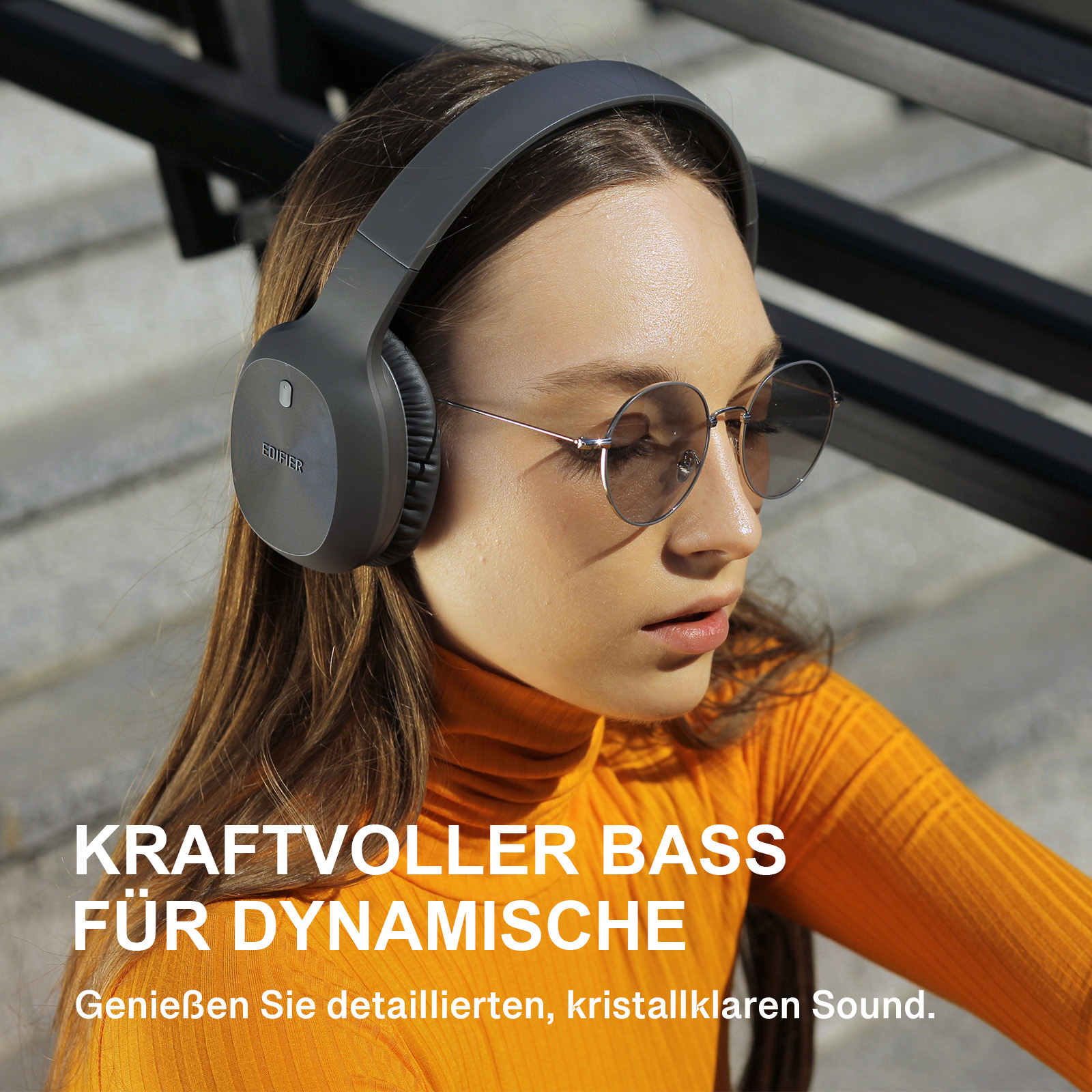 Kobieta w szarych słuchawkach i okularach przeciwsłonecznych, z niemieckim tekstem.