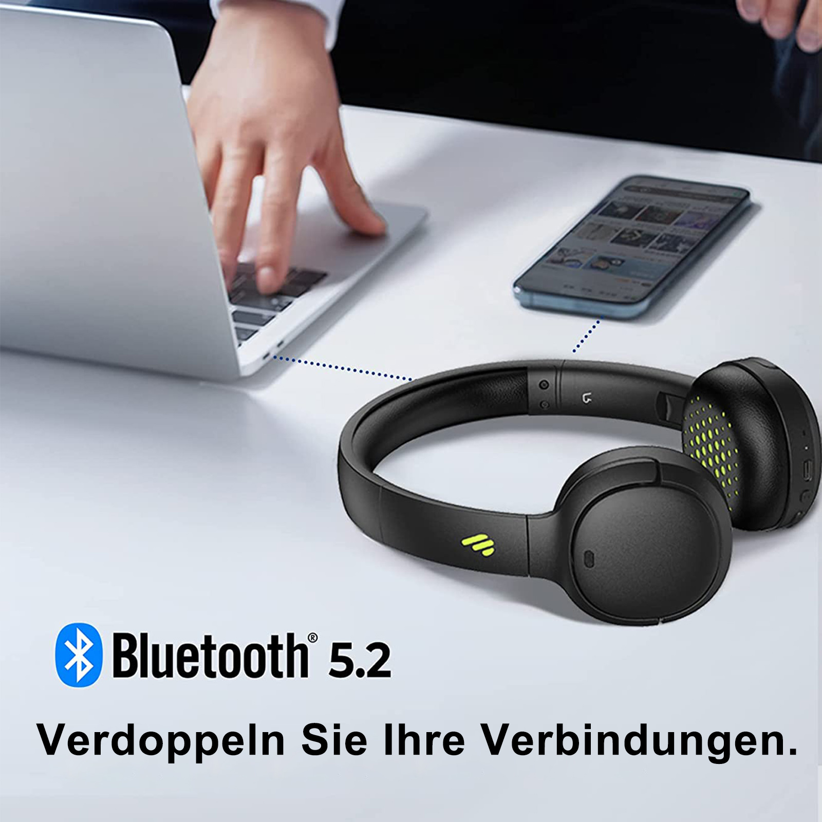 Cuffie nere accanto a un laptop e un telefono.