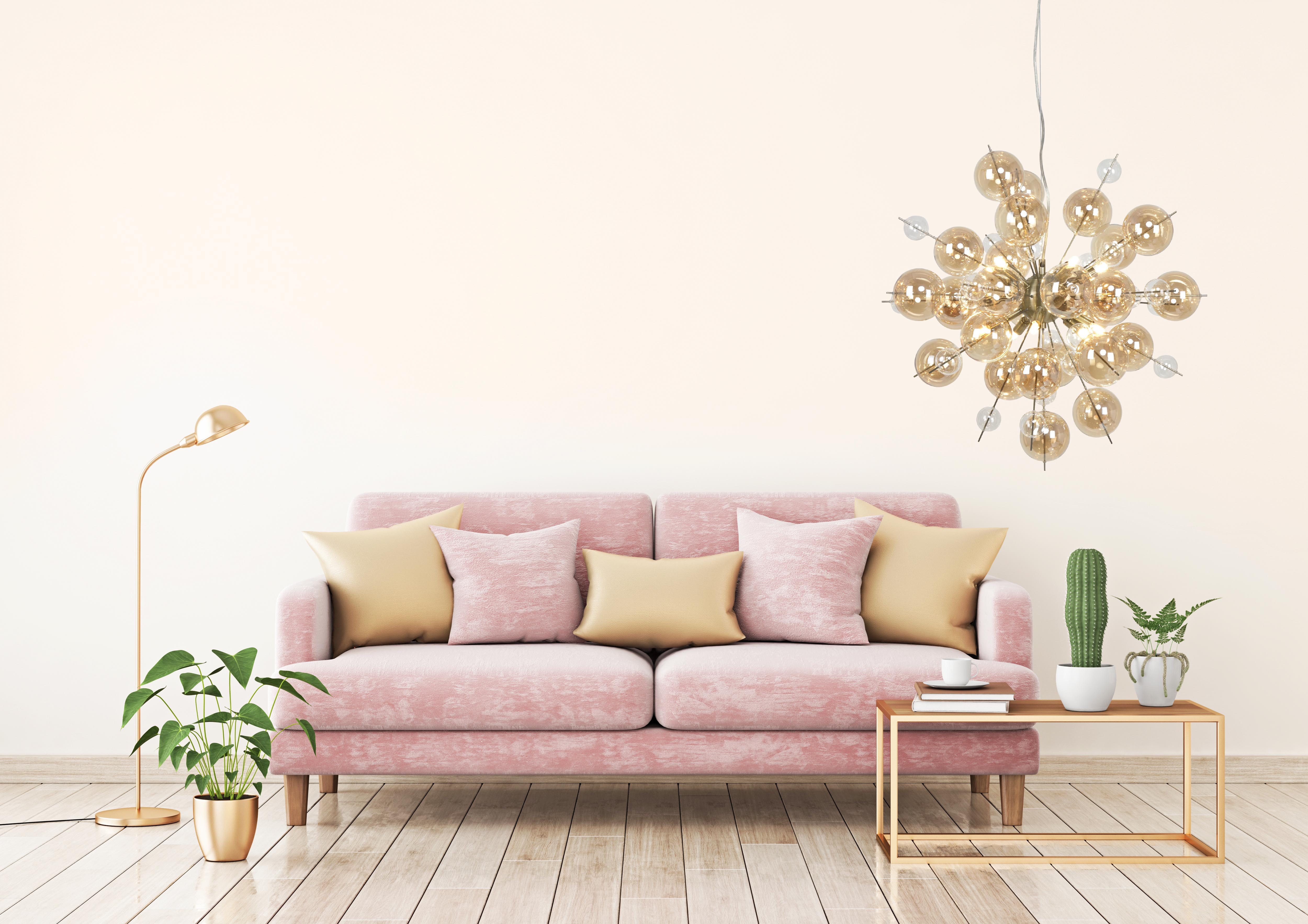 Wohnzimmer mit rosa Sofa, goldenen Akzenten und einem Kronleuchter.