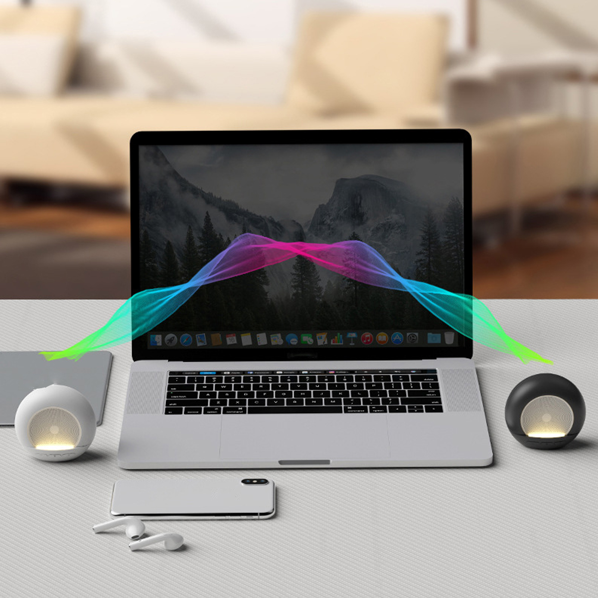 Laptop mit farbenfrohen Soundwellen-Grafiken zwischen zwei Lautsprechern und einem Telefon. Verschwommener Hintergrund eines Raumes.