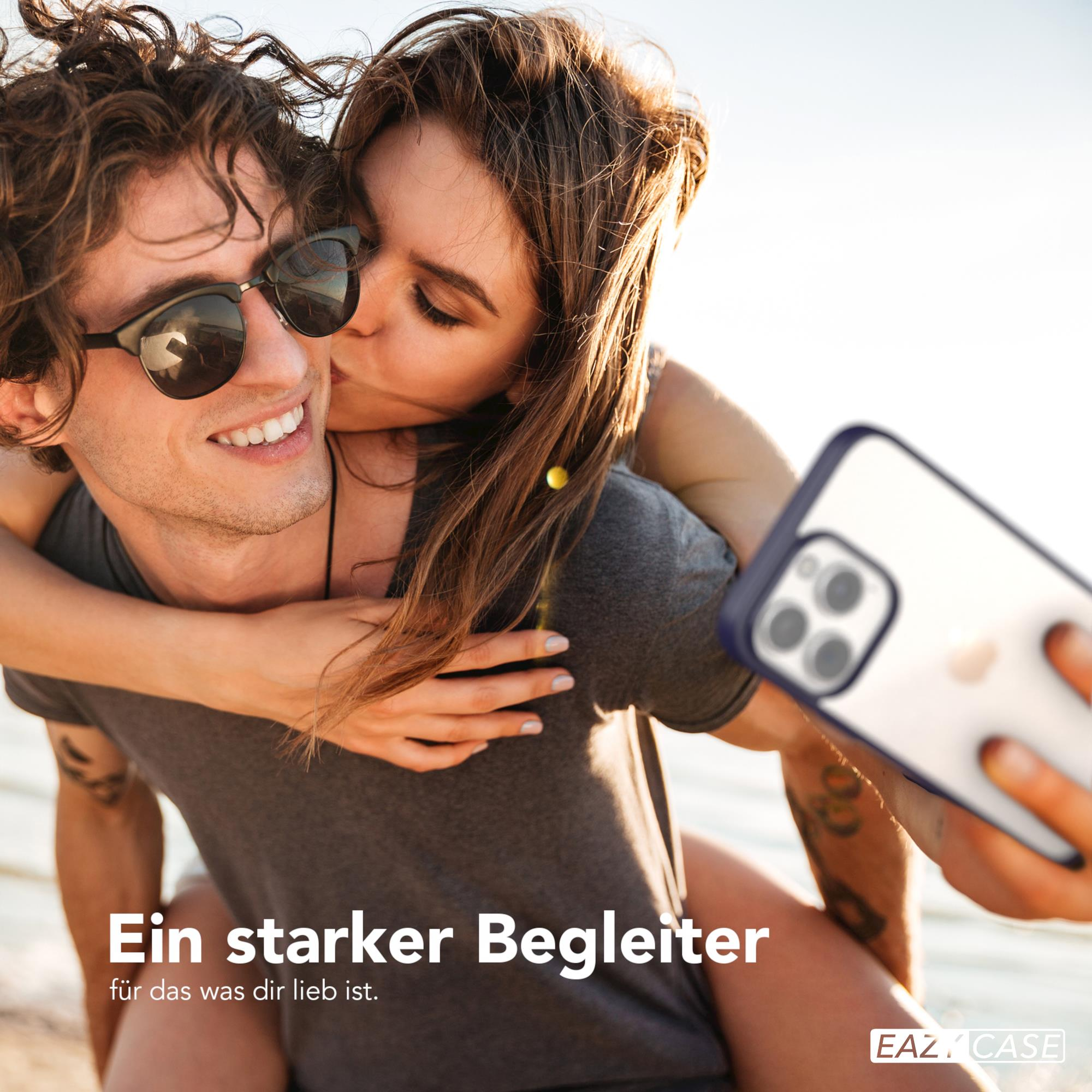 Eine Frau küsst einen Mann von hinten, hält ein Telefon für ein Selfie, Strandhintergrund.